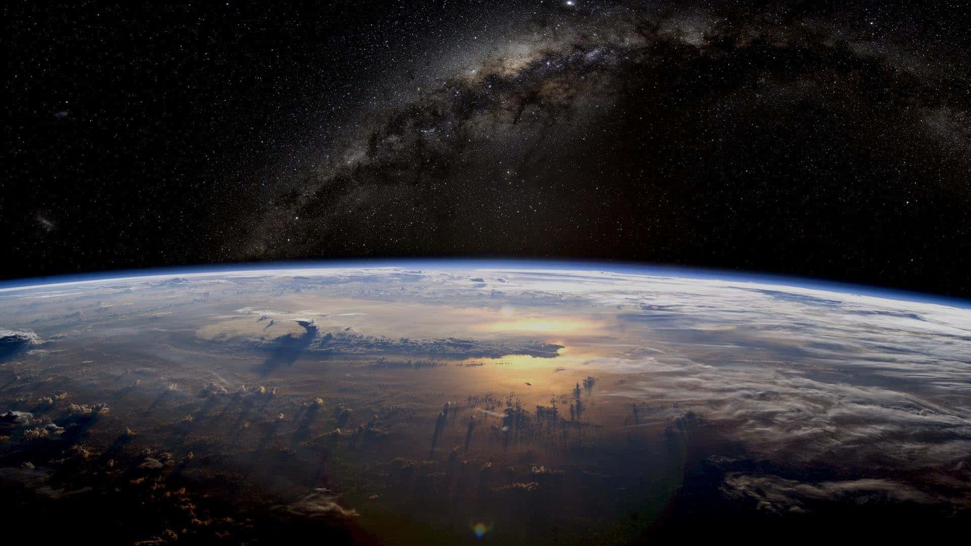 銀河 桌布 壁紙 — 地球在星空下彎曲，銀河在雲層和海洋上空拱起。