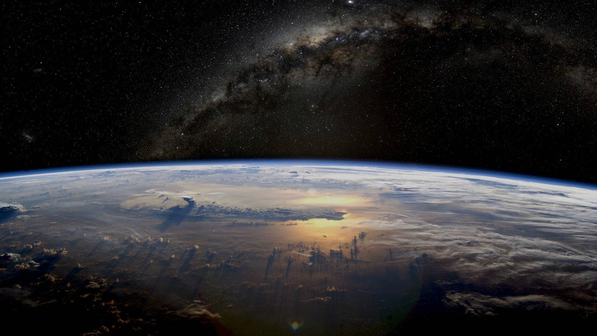 Yahoo 桌布 壁紙 — 地球在星空下彎曲，銀河在頭頂拱起，陽光在雲層上閃爍。