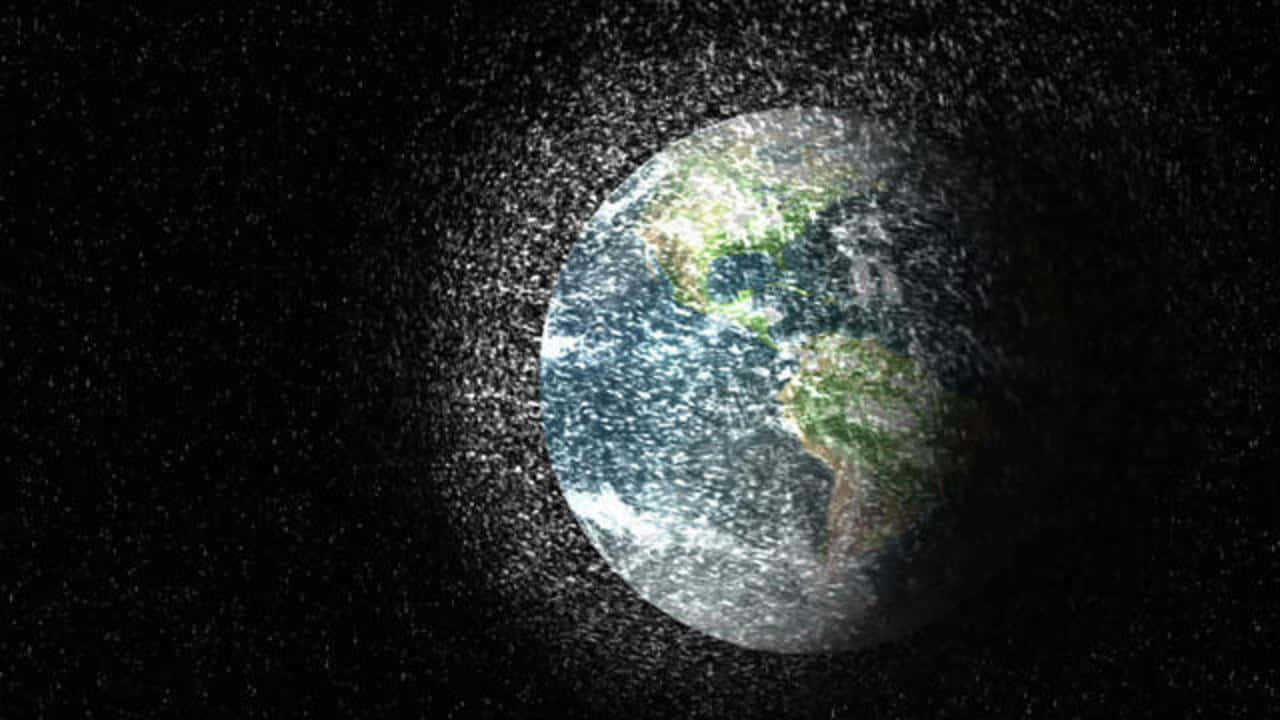Space Debris 桌布 壁紙 — 地球在黑暗的宇宙中柔和地發光，被閃爍的星星和宇宙塵埃光環包圍。