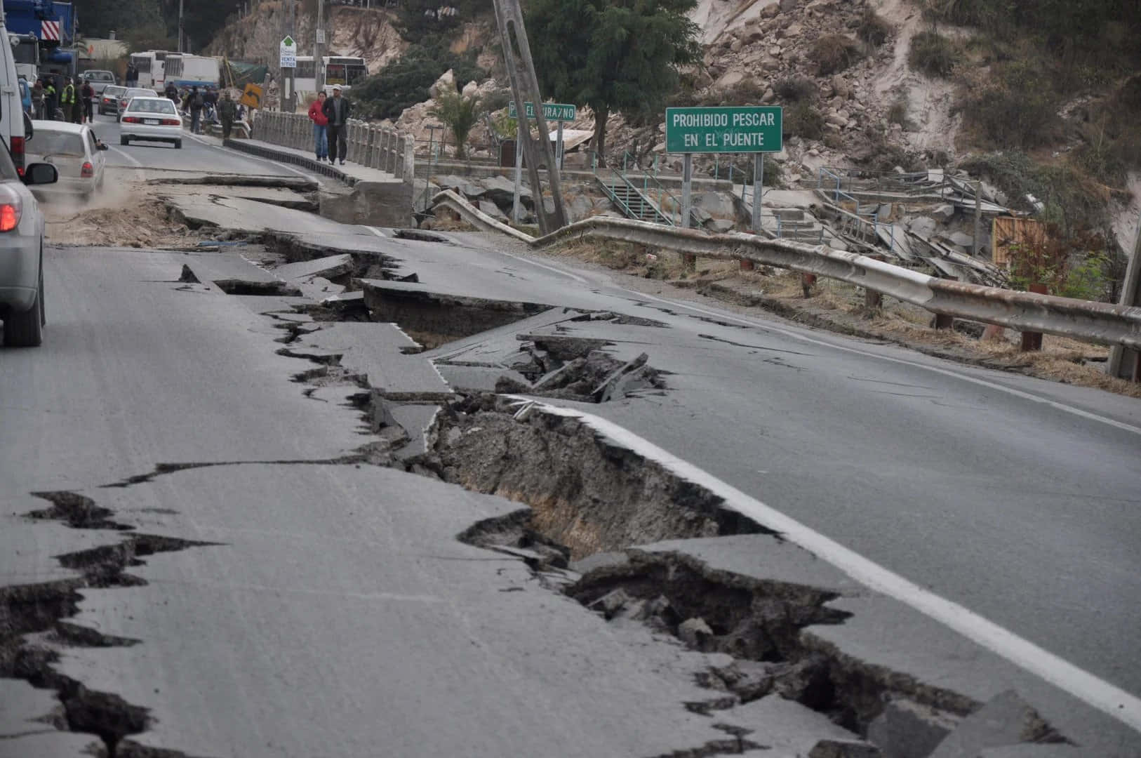 Natural Disaster 桌布 壁紙 — 地震後破裂倒塌的道路，損壞的橋樑附近有緊急車輛和人群。