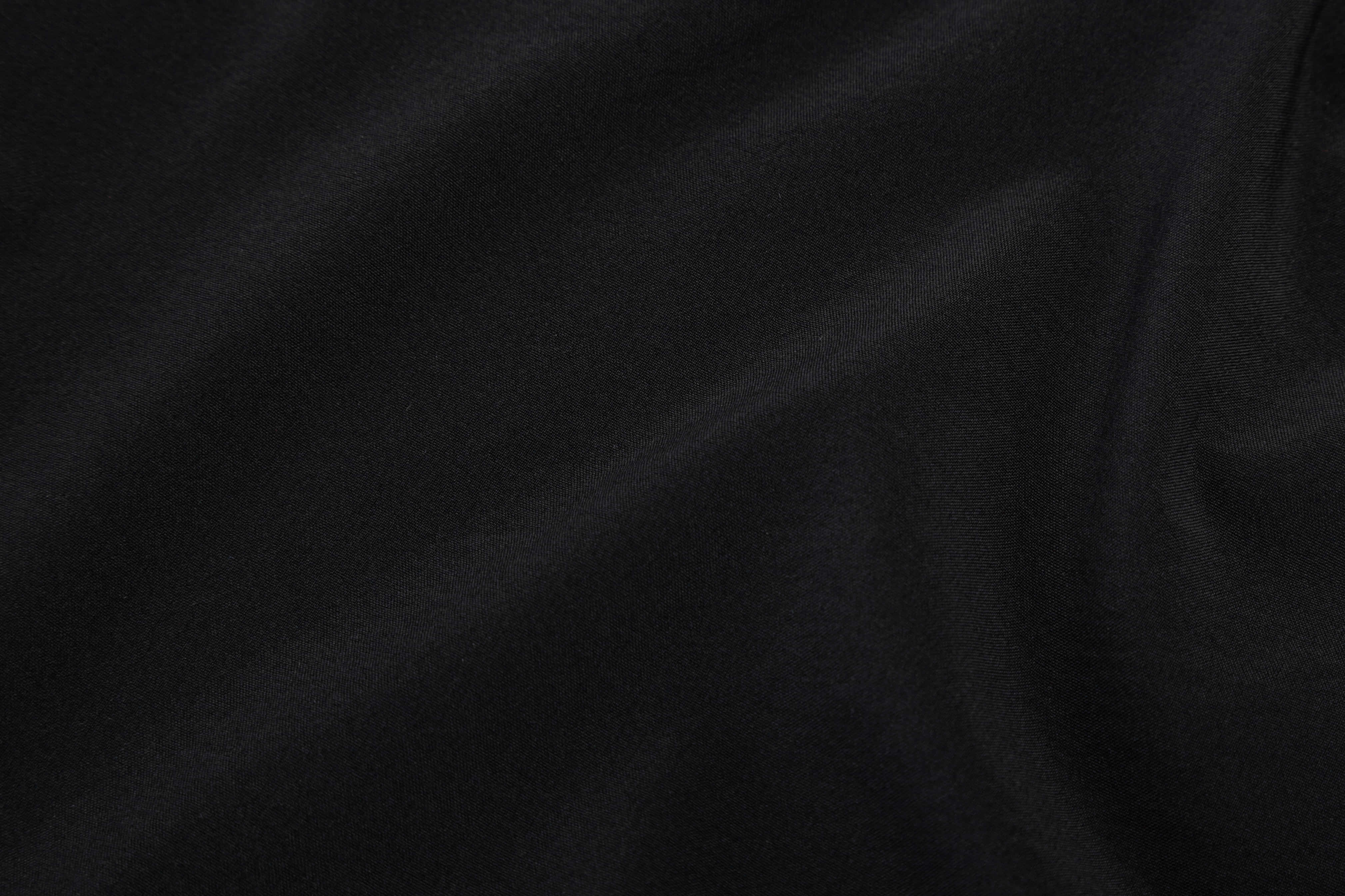 Fabric 桌布 壁紙 — 均勻光線下光滑黑色布料帶有柔和皺褶和細微紋理的近距離特寫。