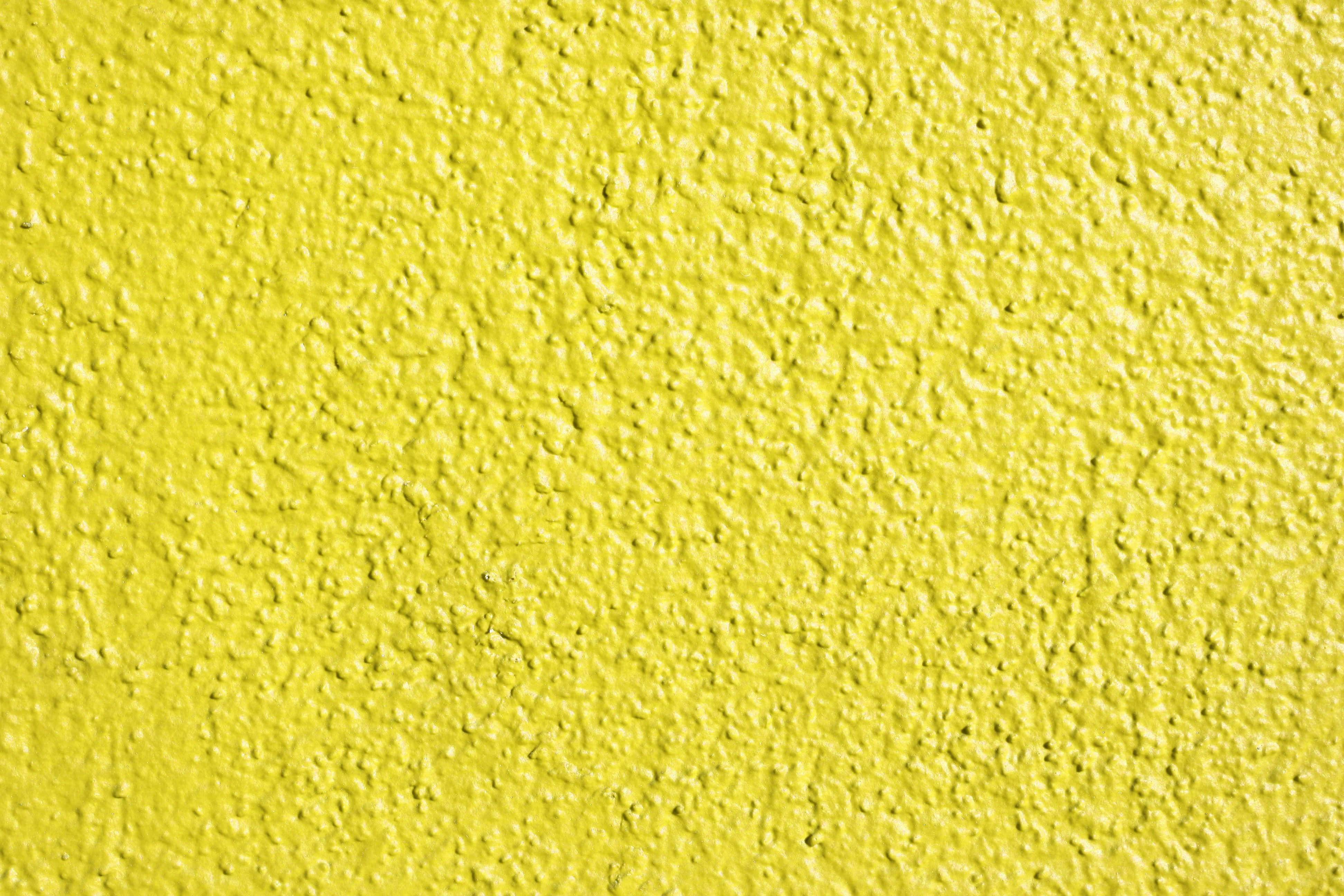 Paint Texture 桌布 壁紙 — 均勻光線下粗糙灰泥飾面的鮮黃色紋理牆壁特寫。
