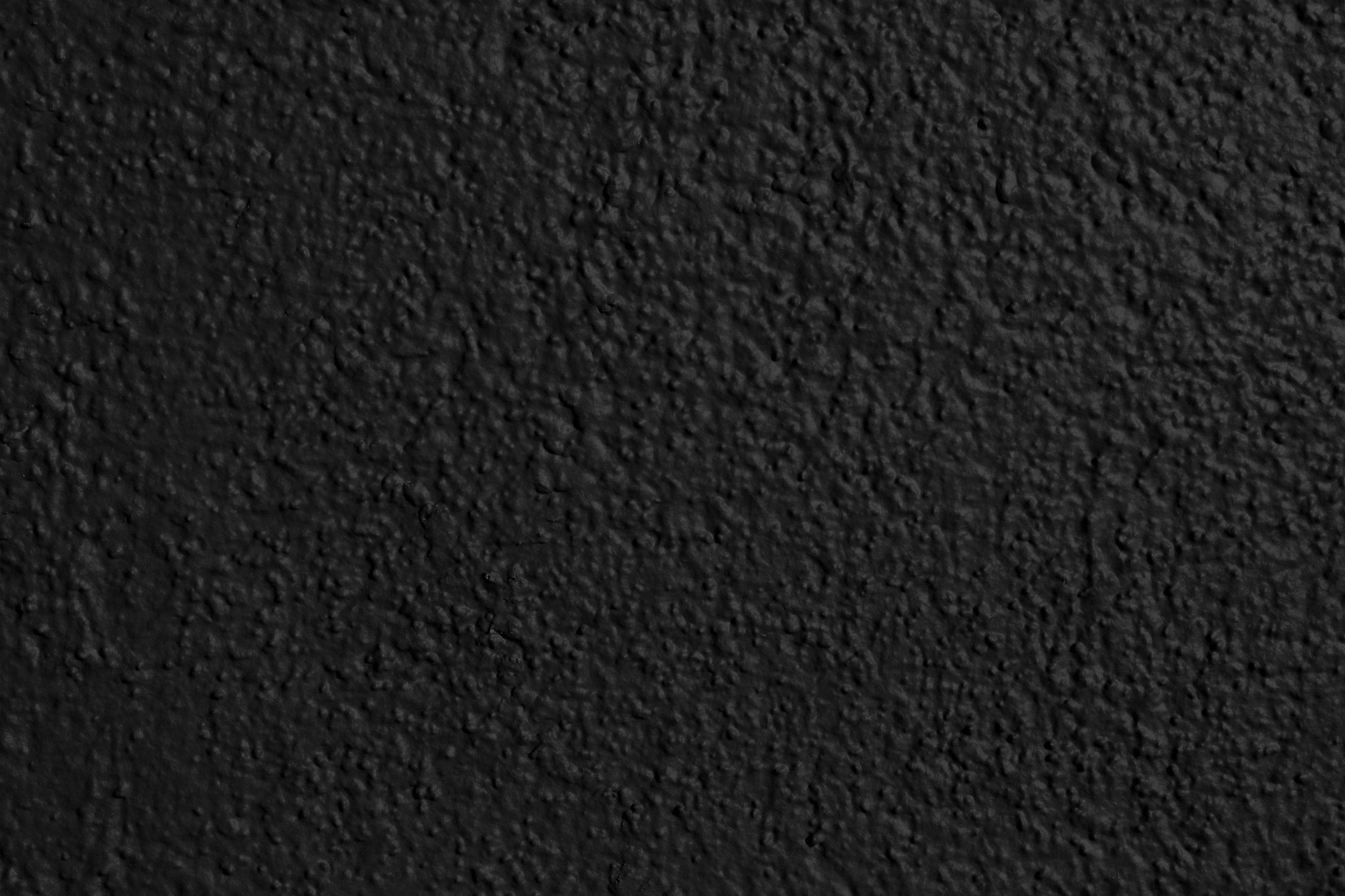 Pain Black And White 桌布 壁紙 — 均勻光線下粗糙黑色灰泥牆的特寫，帶有細微紋理變化。