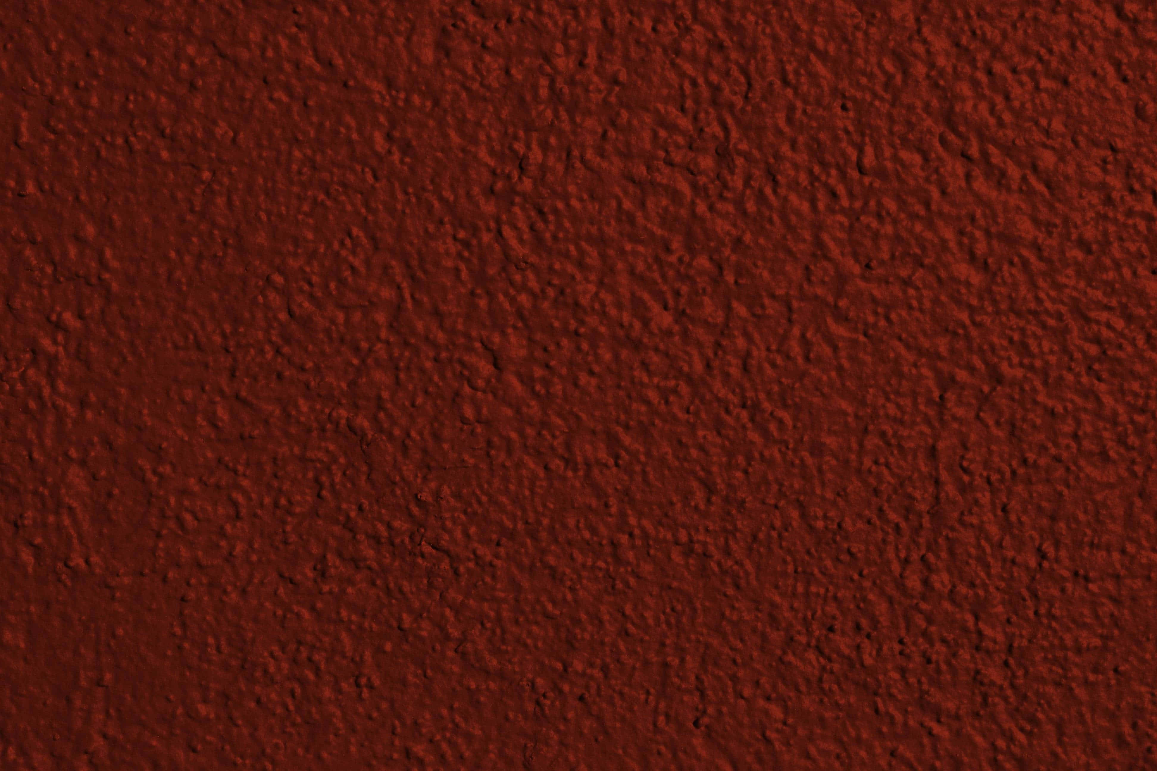 Red Texture 桌布 壁紙 — 均勻照明下粗糙灰泥飾面的豐富酒紅色紋理牆壁特寫。
