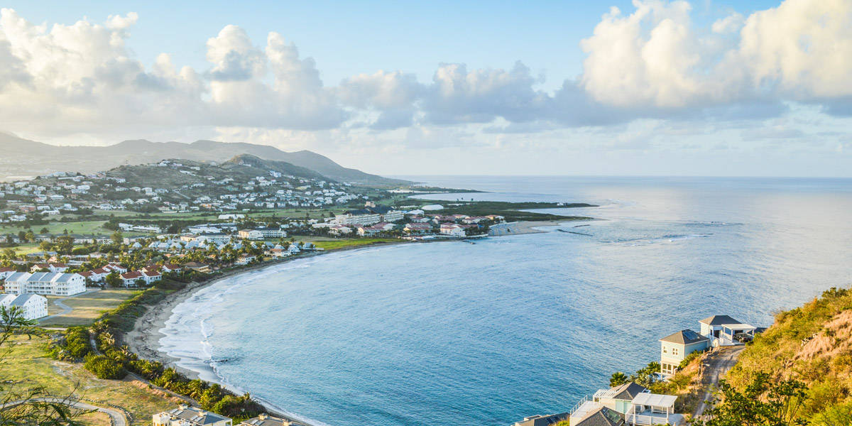 Caribbean 桌布 壁紙 — 坐落於海灣中的沿海小鎮，擁有碧綠海水和白色房屋，天空部分多雲。