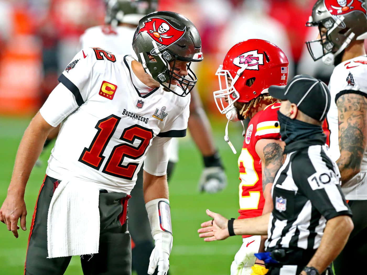 Tyrann Mathieu 桌布 壁紙 — 坦帕灣海盜隊四分衛湯姆·布雷迪身穿白色12號球衣，在夜間NFL比賽中與裁判交談。