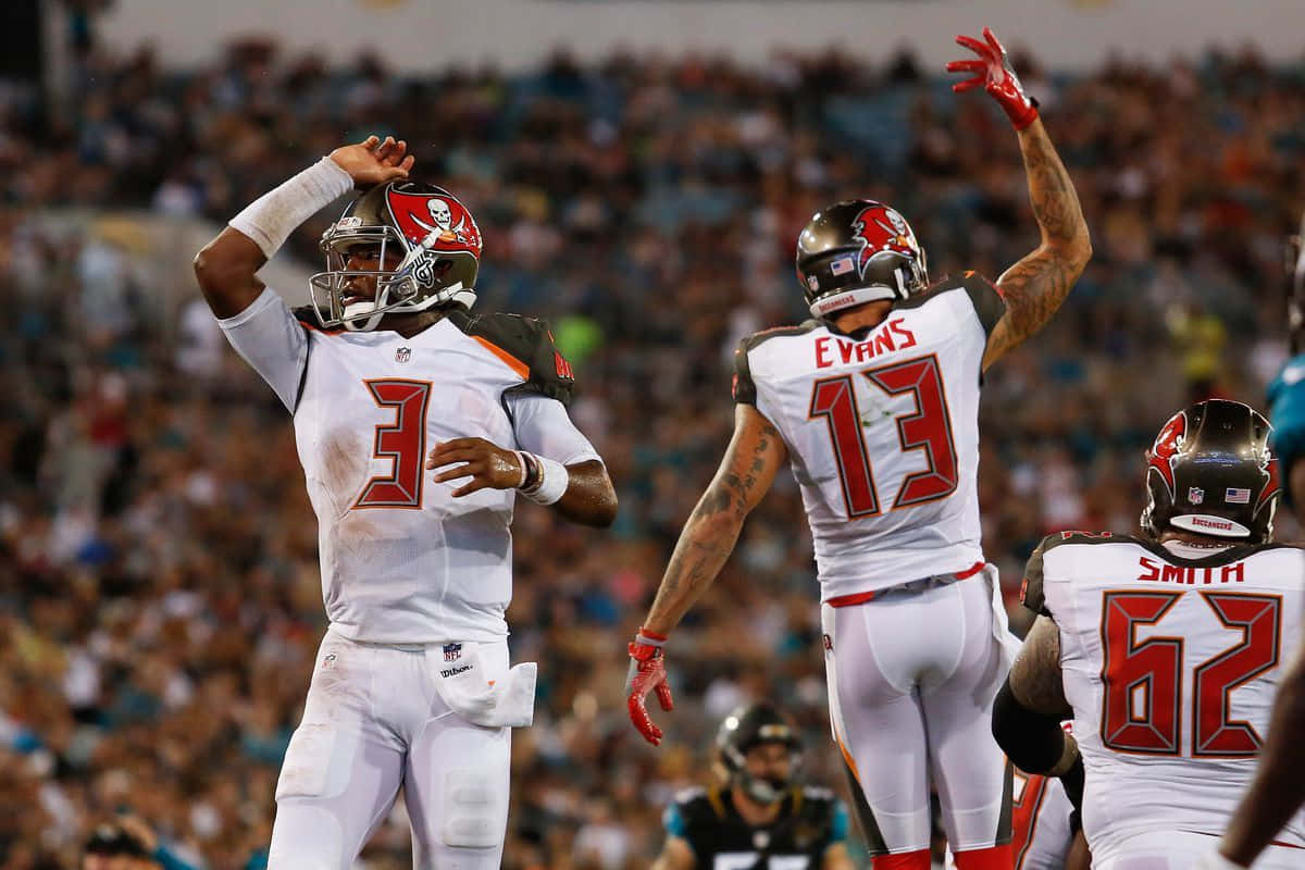 Mike Evans 桌布 壁紙 — 坦帕灣海盜隊球員在燈火通明的足球場上慶祝達陣，背景是喧囂的人群。