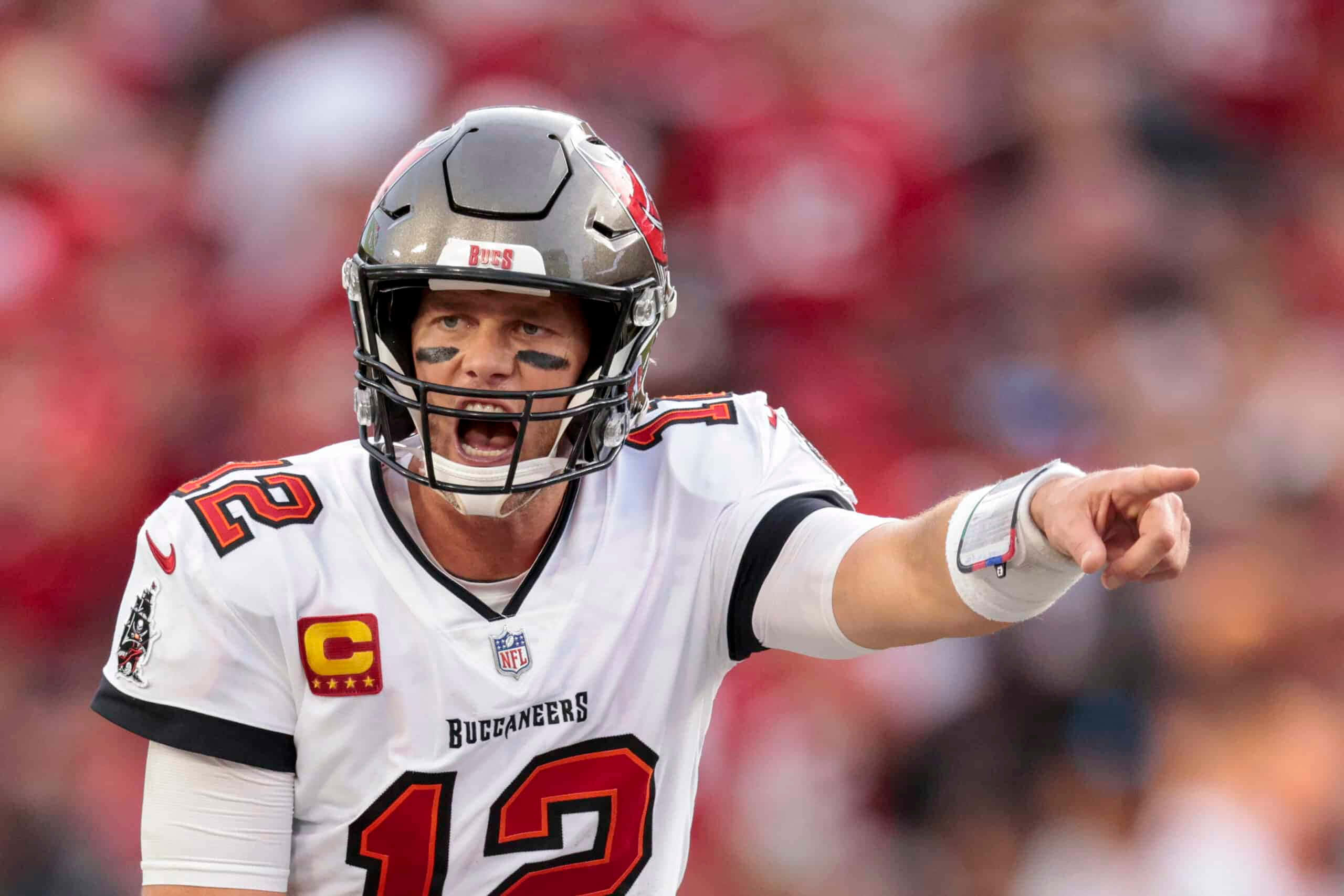 NFL 桌布 壁紙 — 坦帕灣海盜隊的四分衛身穿白色12號球衣，在日間NFL比賽中大喊並指著，背景是模糊的紅色人群。