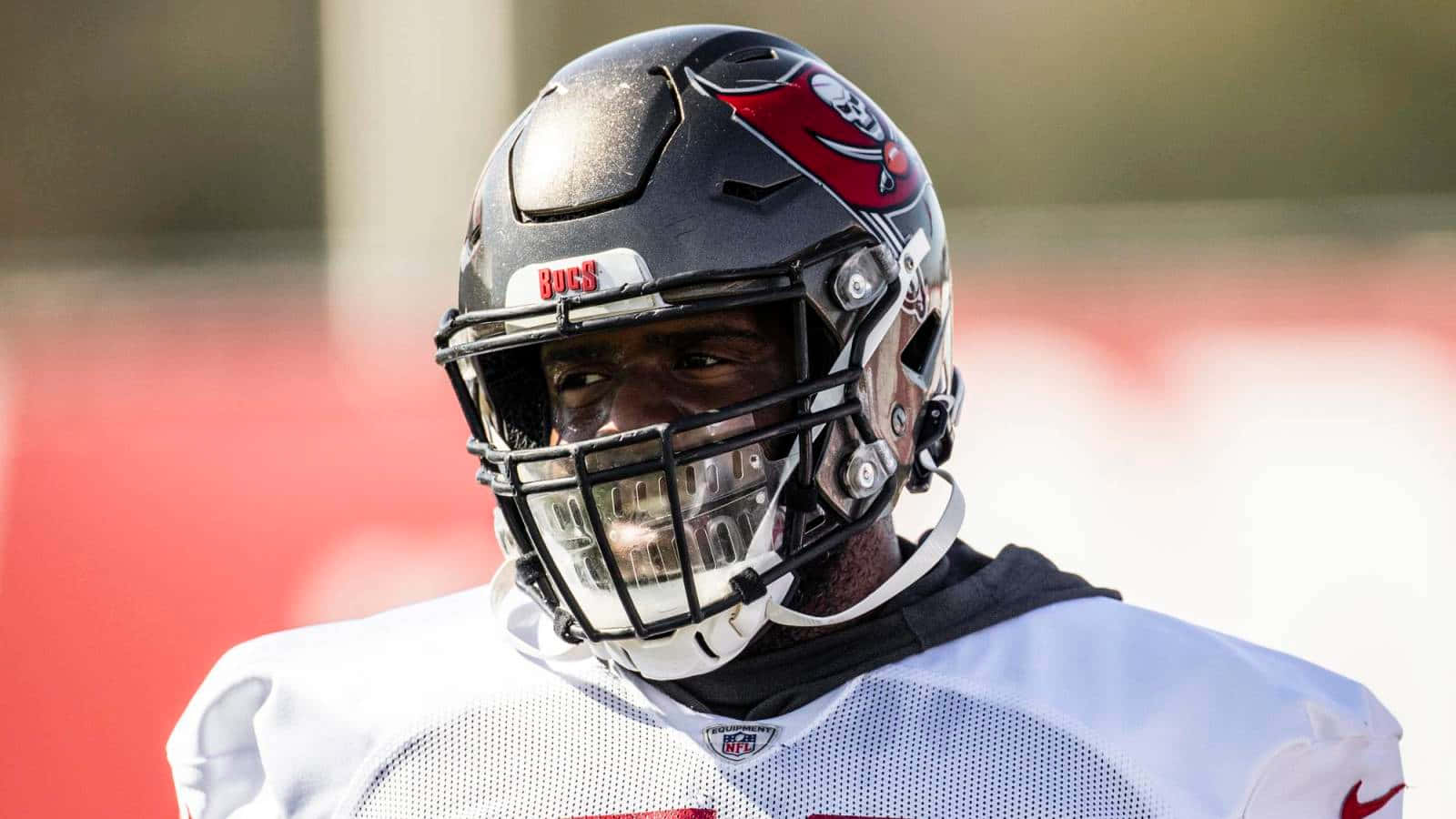 Buccaneers 桌布 壁紙 — 坦帕灣海盜隊美式足球員身穿白色球衣和頭盔，在陽光明媚的球場上專注地向前看的特寫。