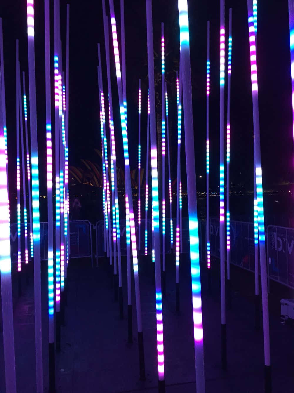 Installation Art 桌布 壁紙 — 垂直LED燈棒在戶外活動的黑暗夜空中發出鮮豔的紫色和藍色圖案光芒。