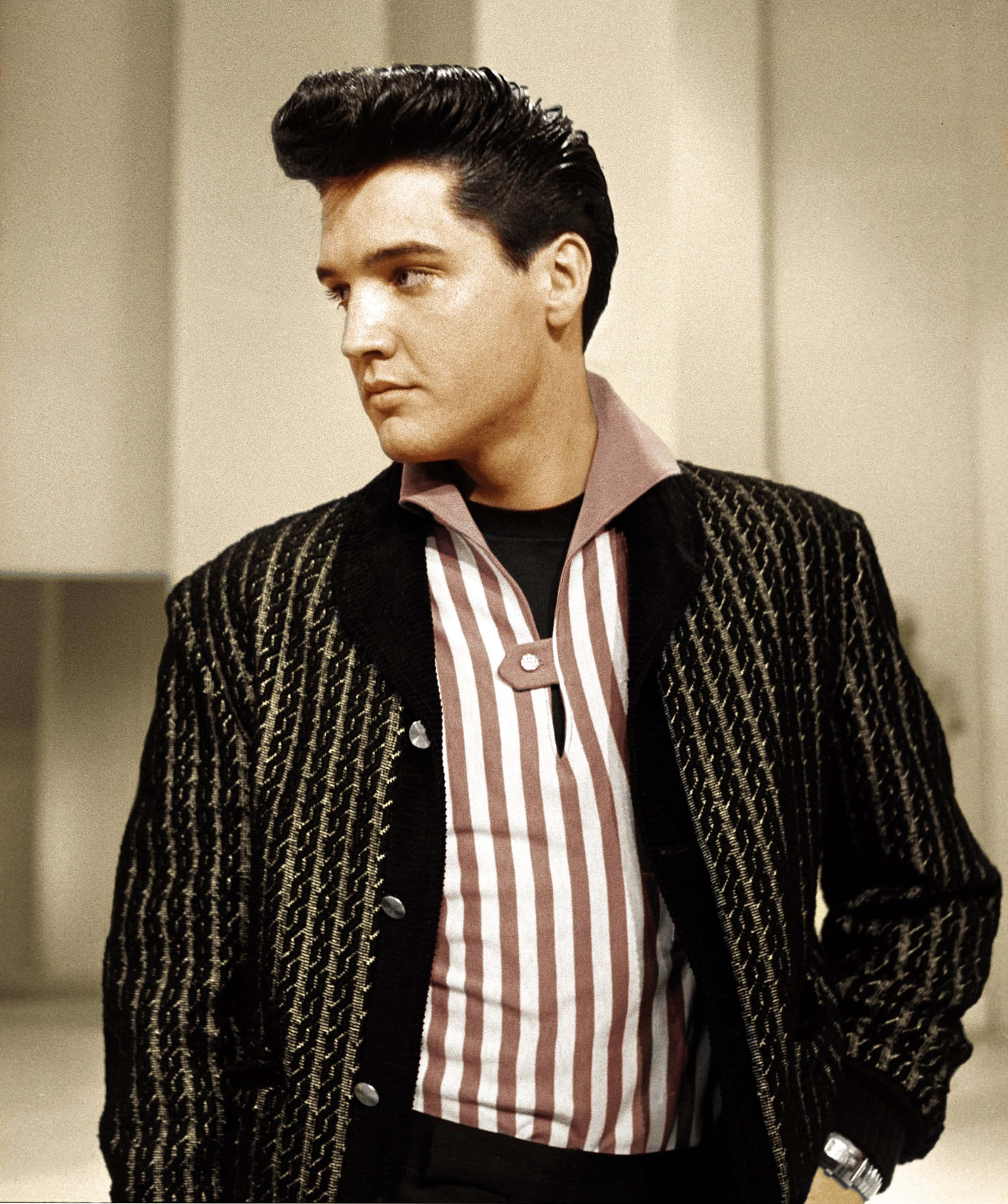 Elvis 桌布 壁紙 — 埃爾維斯·普里斯萊身穿質感黑色外套和條紋襯衫，在純色攝影棚背景前表情嚴肅。