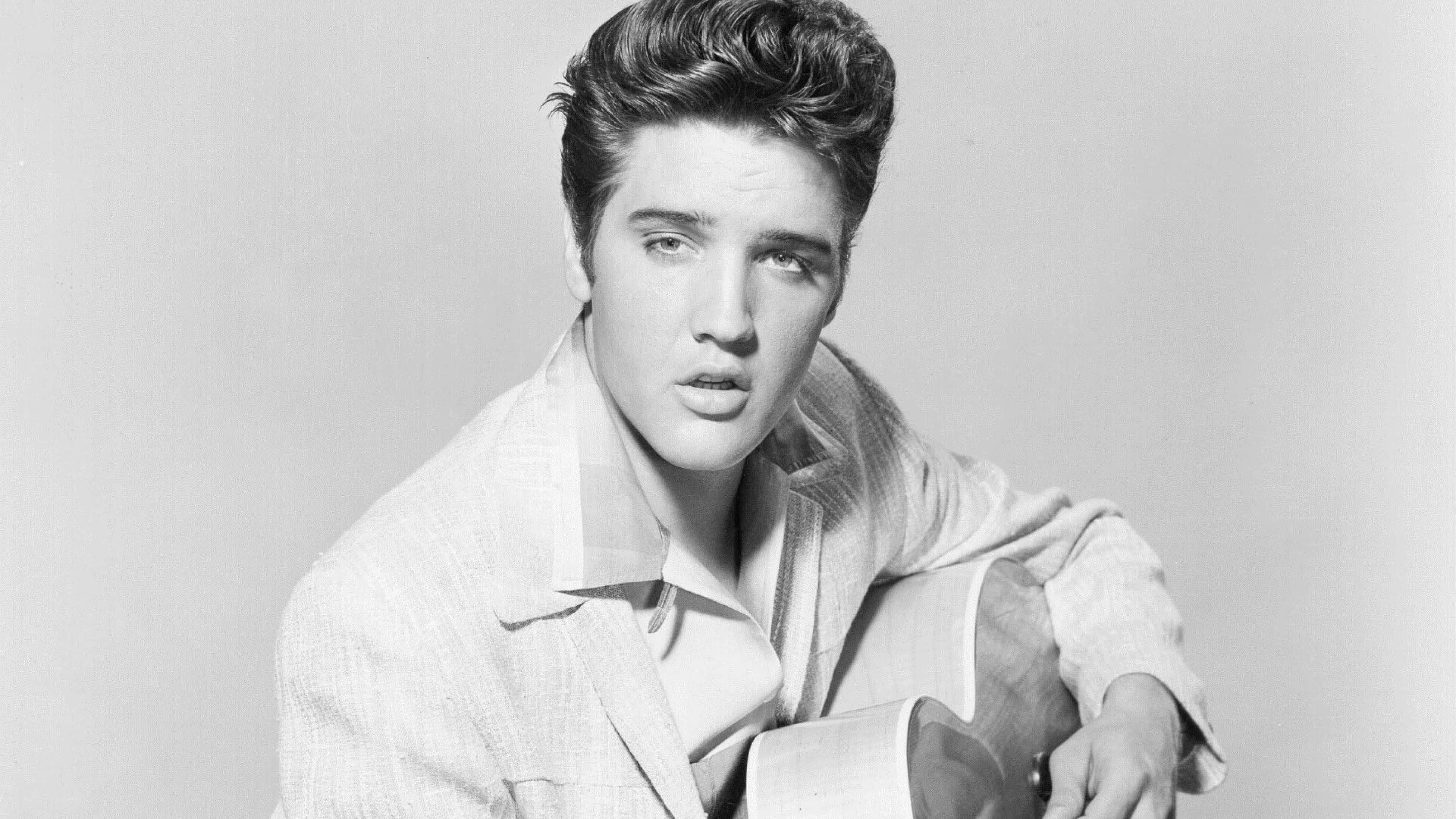 Elvis 桌布 壁紙 — 埃爾維斯·普雷斯利專注地凝視，手持吉他，經典黑白攝影棚肖像。