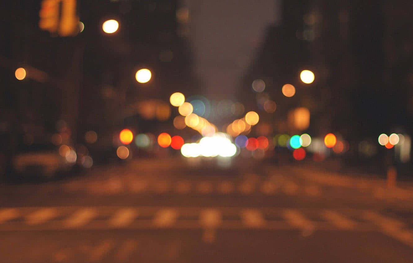 Bokeh 桌布 壁紙 — 城市交通的散景燈光在夜晚的黑暗城市街道上溫暖地發光。