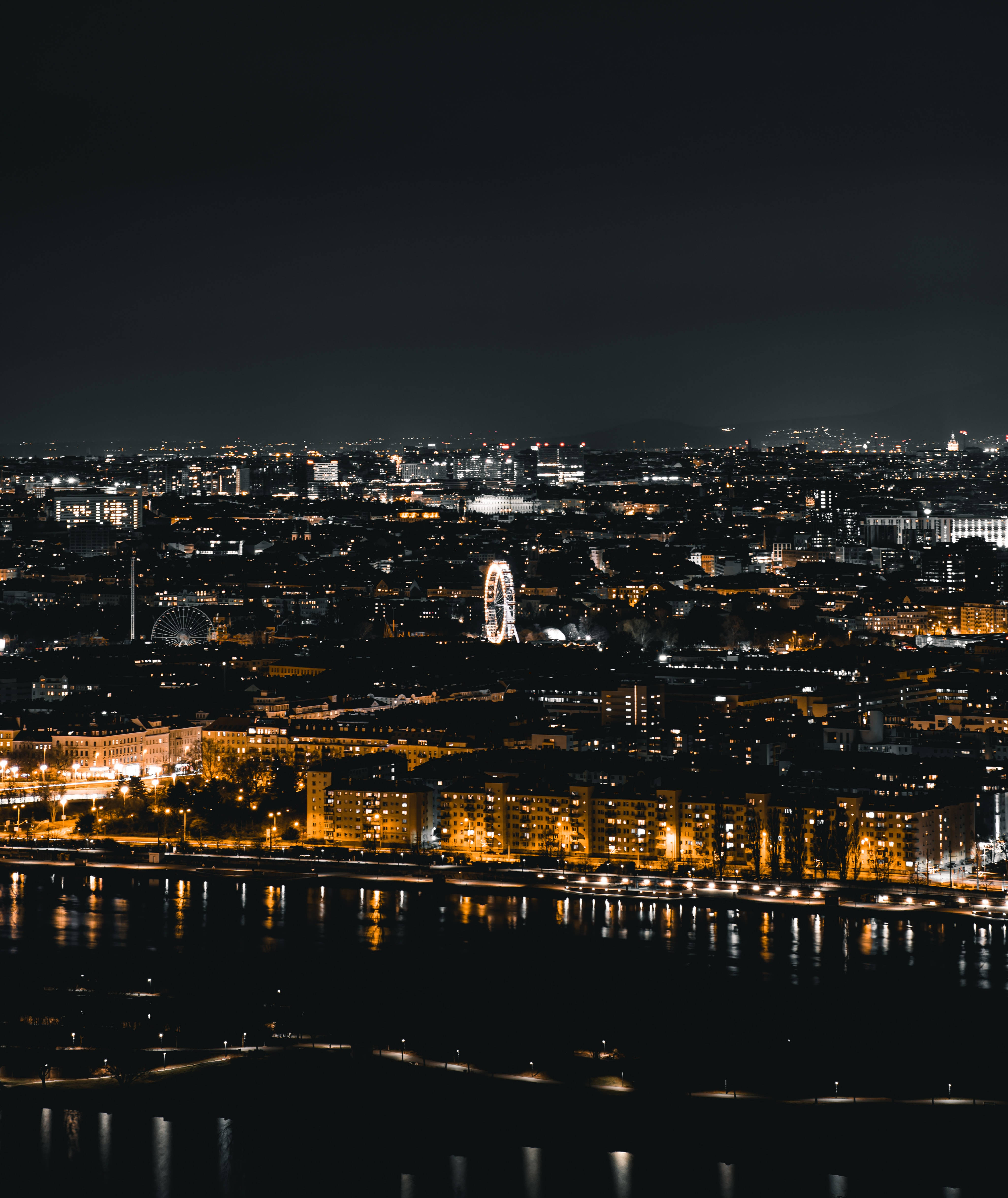 lights 桌布 壁紙 — 城市全景夜景，閃爍的燈光倒映在水面上，並有一個顯眼的摩天輪。