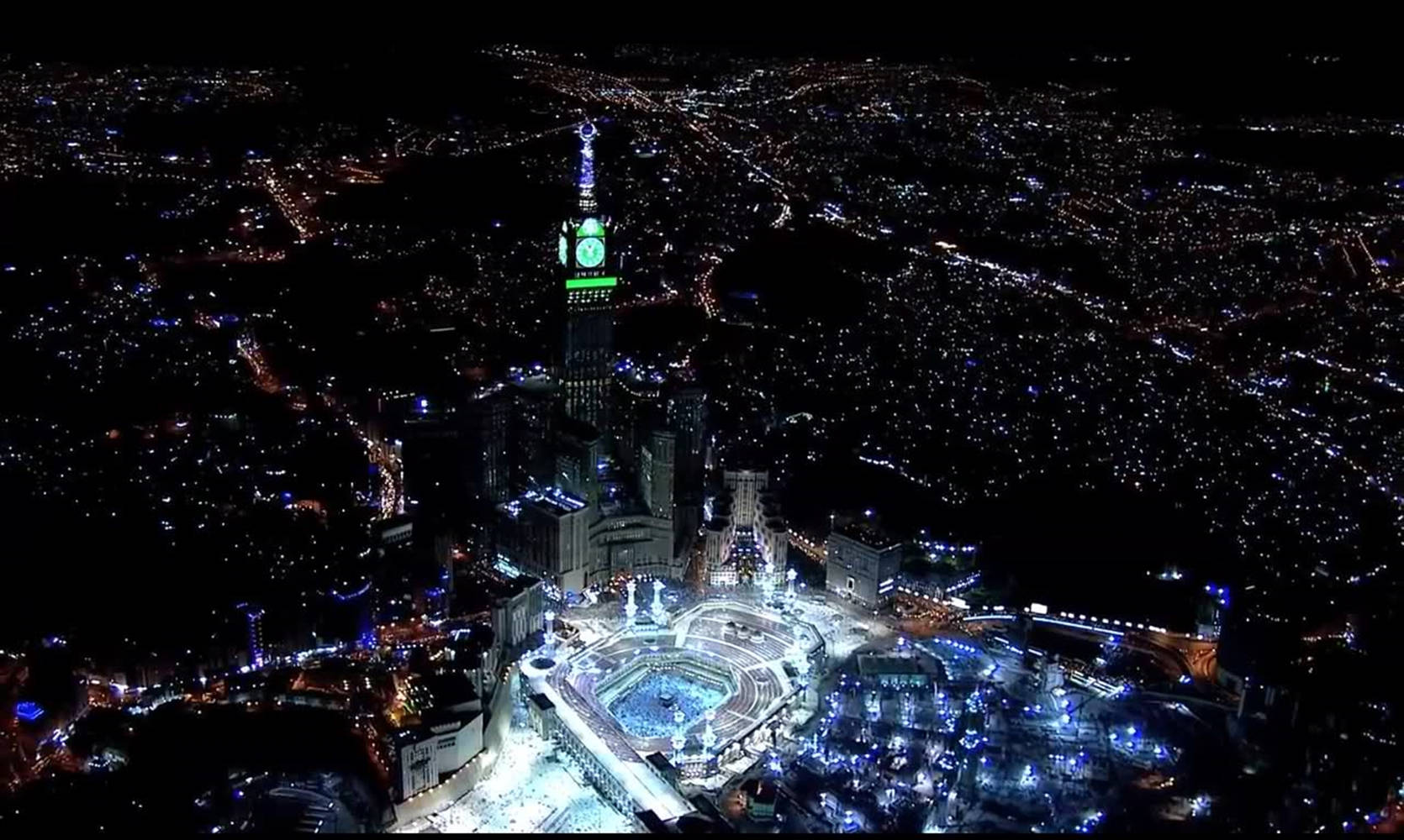 muslim 桌布 壁紙 — 城市夜景鳥瞰圖，帶有發光的綠色鐘樓和下方明亮的街道。