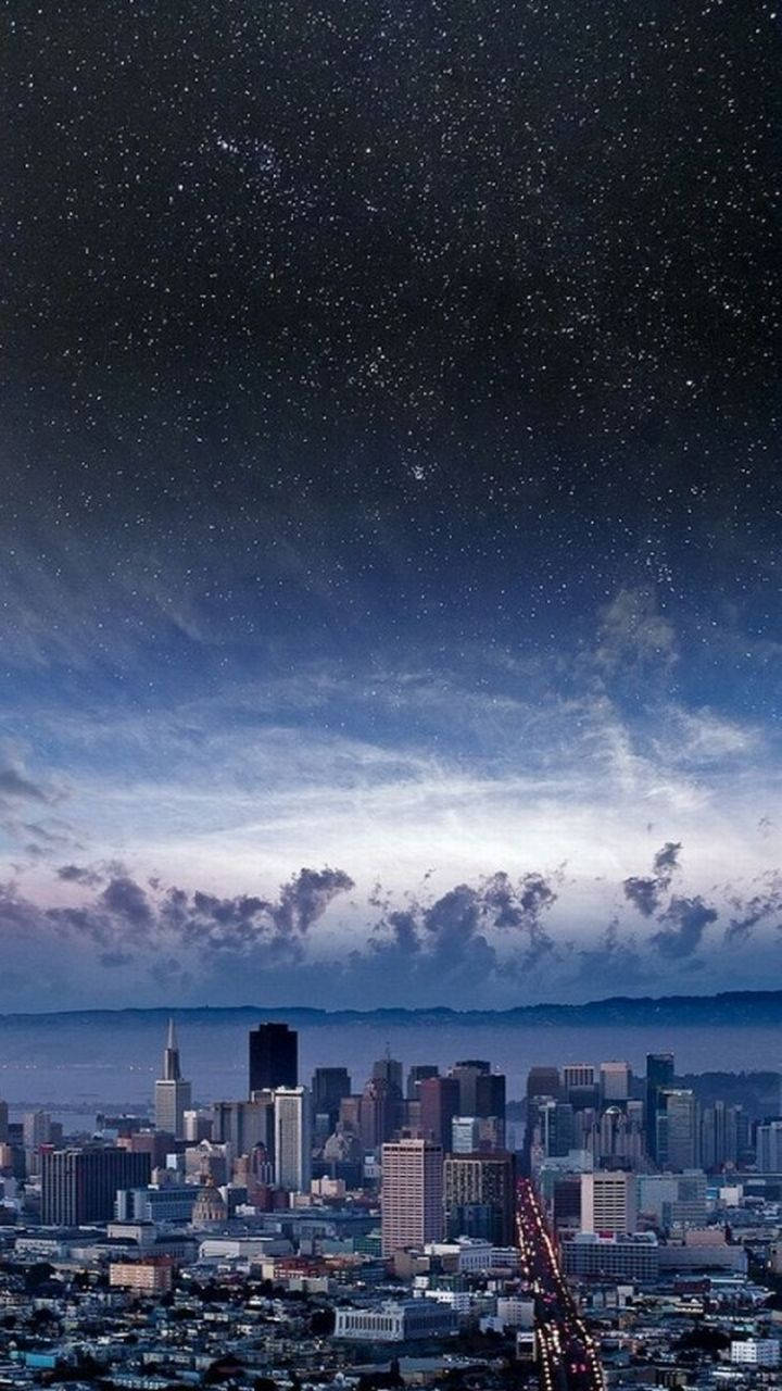 Nyc Phone 桌布 壁紙 — 城市天際線，星空下閃爍的街燈和縷縷雲彩。