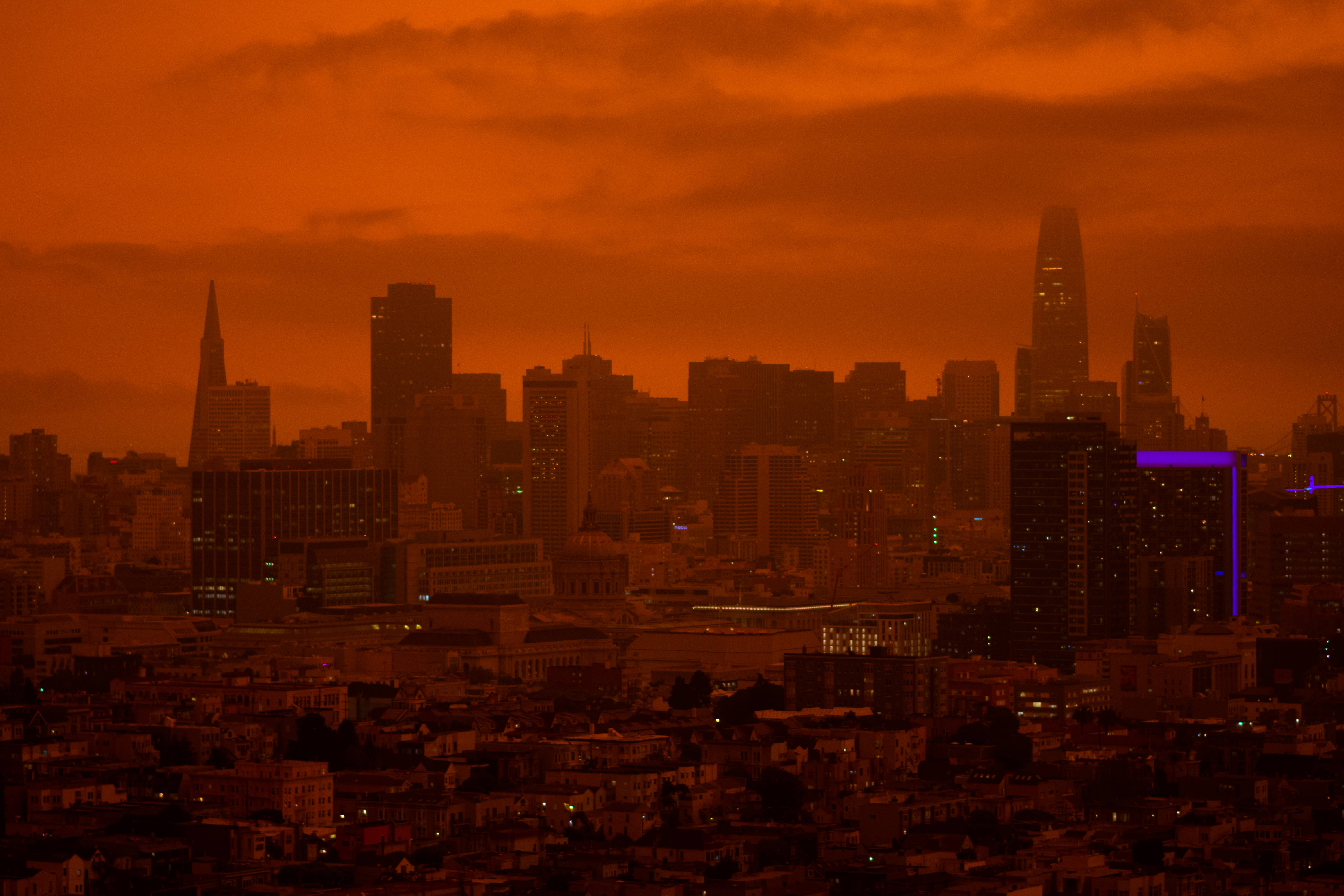 火星 桌布 壁紙 — 城市天際線沐浴在熾熱夕陽的強烈橙色光芒中，在密集的城市建築上投下長長的陰影。
