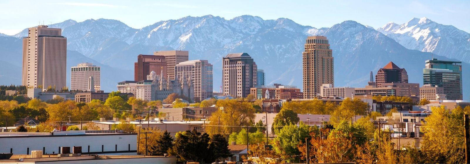 Salt Lake City 桌布 壁紙 — 城市天際線的全景，現代建築在晴朗藍天下以白雪覆蓋的山脈為背景。