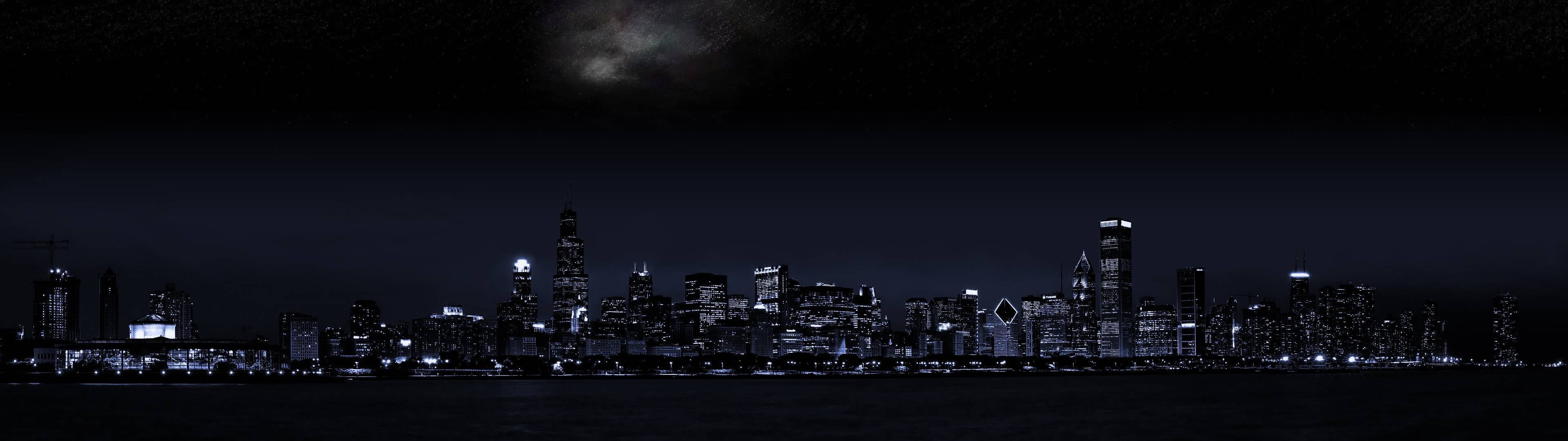 3840x1080 HD dual monitor 桌布 壁紙 — 城市天際線的夜間全景，帶有發光的窗戶和上方陰暗多雲的天空。
