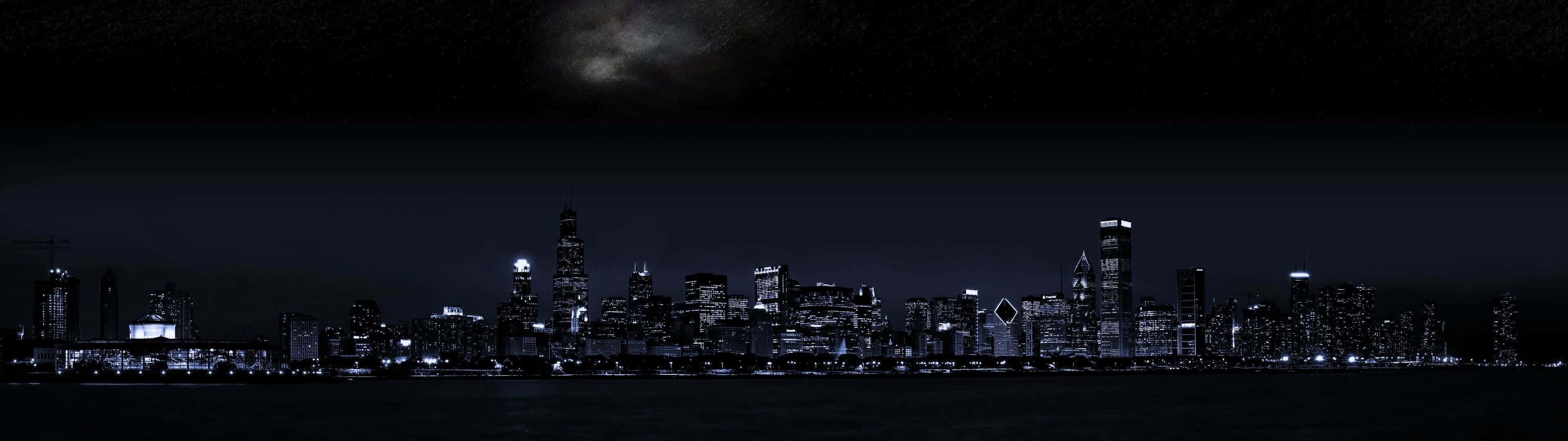 City Night 桌布 壁紙 — 城市天際線的夜間全景，窗戶閃爍著光芒，上方是漆黑的天空。