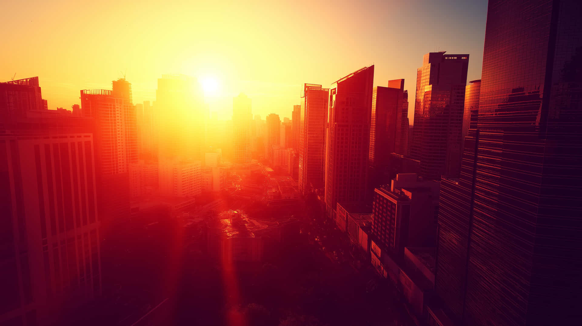 Cityscape Bathed in Warm Sunlight, Urban Horizon View 壁紙 — 城市天際線的鳥瞰圖，沐浴在強烈的金色橙色日落光線中，帶有鏡頭光暈。