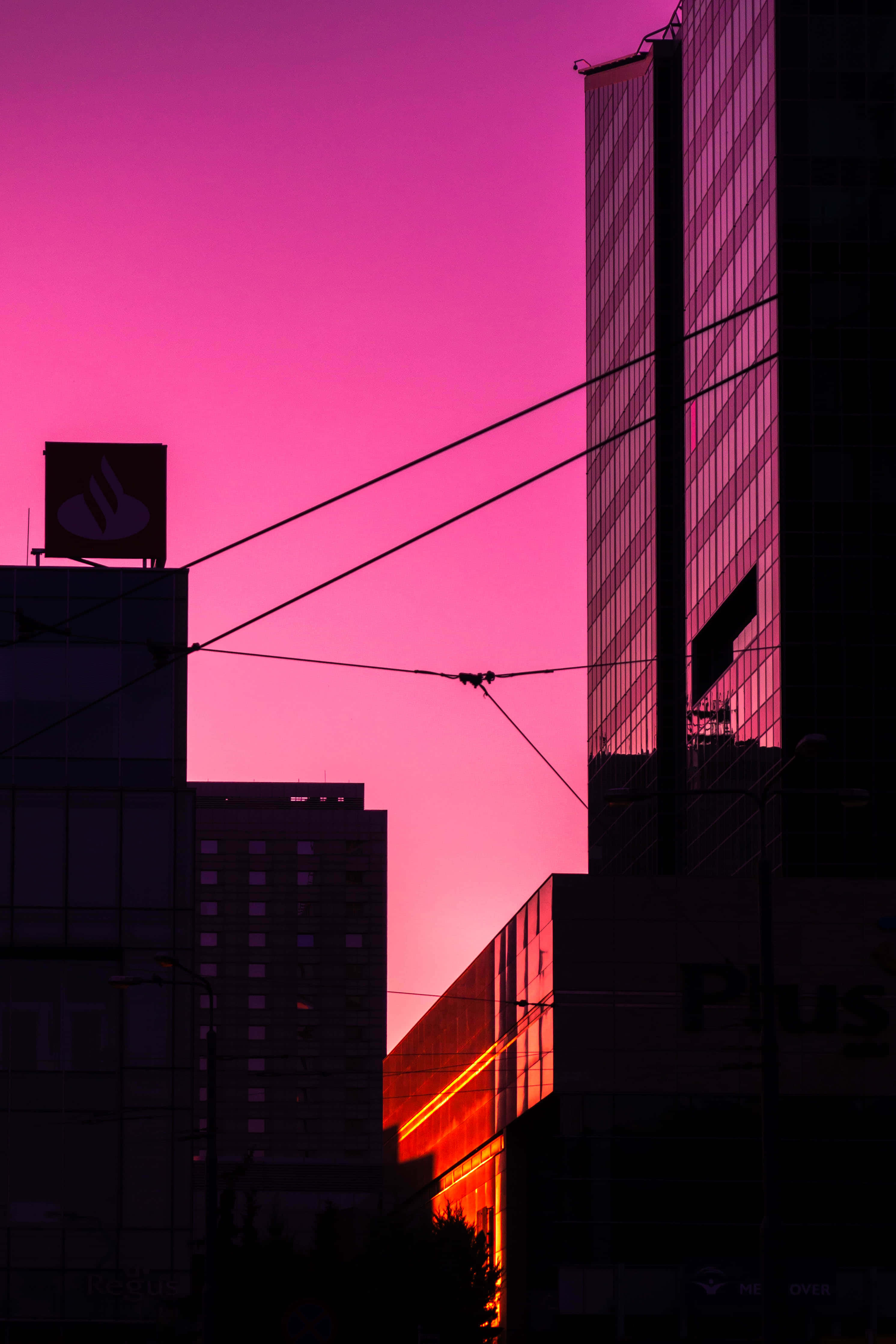 Skyscraper 桌布 壁紙 — 城市建築的剪影，映襯著充滿活力的洋紅色日落天空，較低建築物上有發光的橙色點綴。