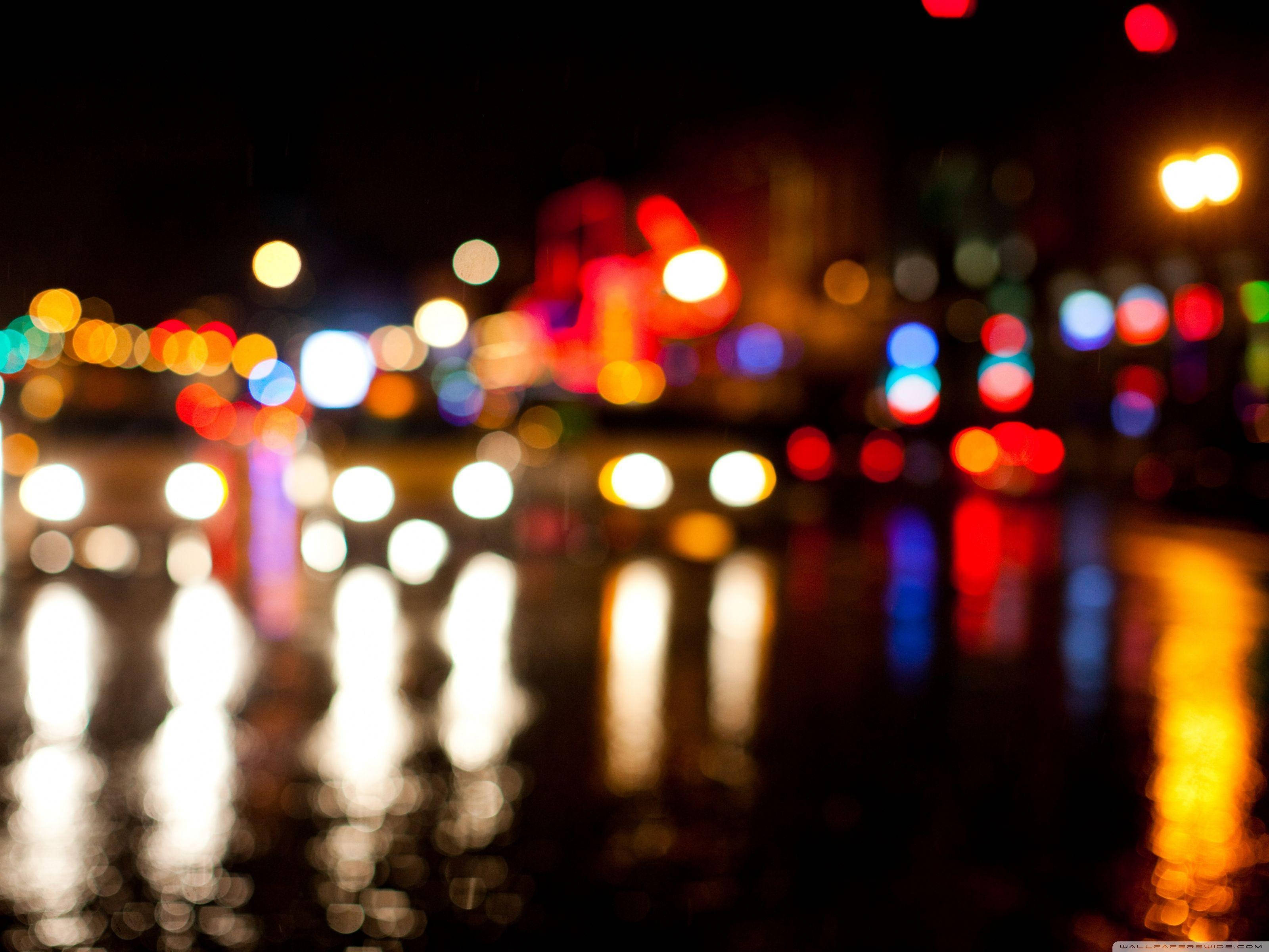 Broadway 桌布 壁紙 — 城市車輛和街燈的散景燈光在夜間潮濕的路面上閃爍，營造出夢幻般的城市光芒。