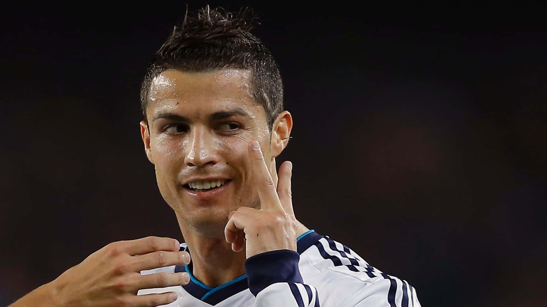 Ronaldo 桌布 壁紙 — 基斯坦奴·朗拿度在明亮燈光下的球場自信微笑並做出和平手勢。