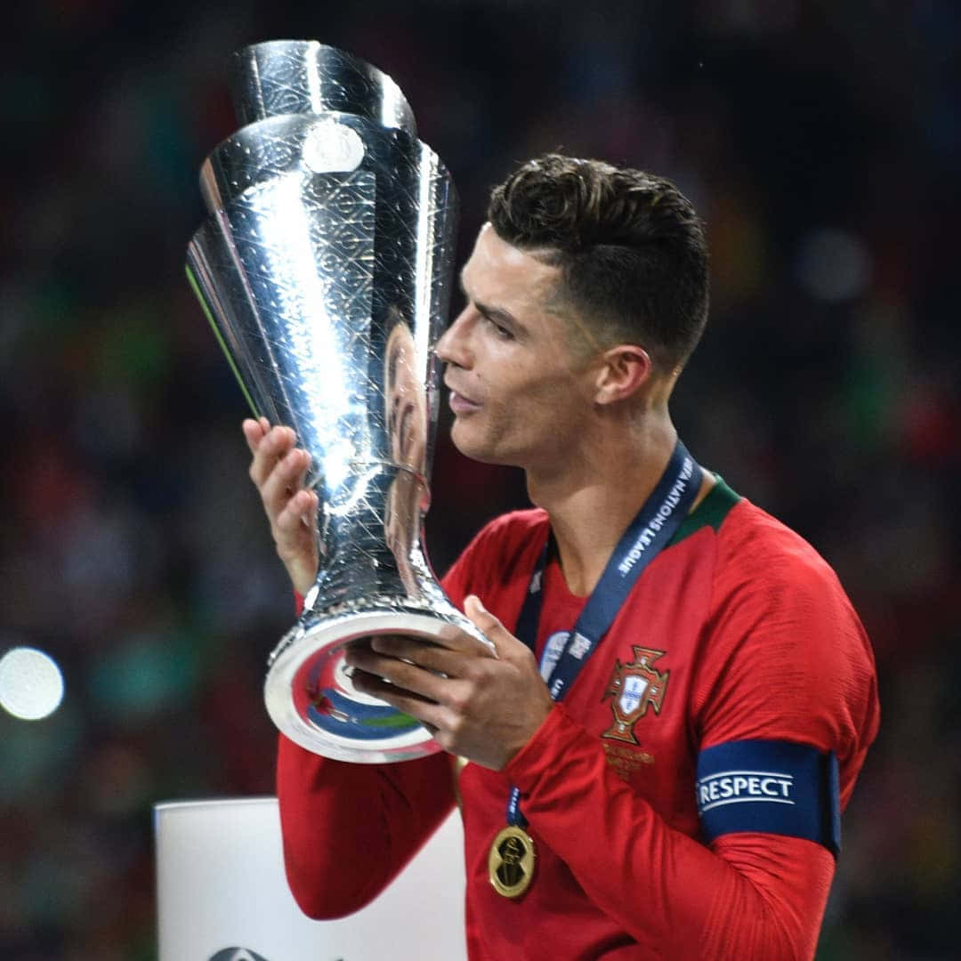 Ronaldo 桌布 壁紙 — 基斯坦奴·朗拿度在球場燈光下穿著葡萄牙紅色球衣親吻歐洲國家聯賽獎盃。