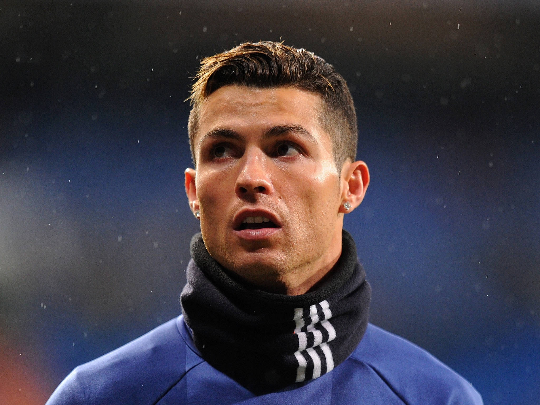 Ronaldo 桌布 壁紙 — 基斯坦奴朗拿度近鏡，身穿藍色運動外套配黑色圍巾，背景為模糊的球場，表情專注。
