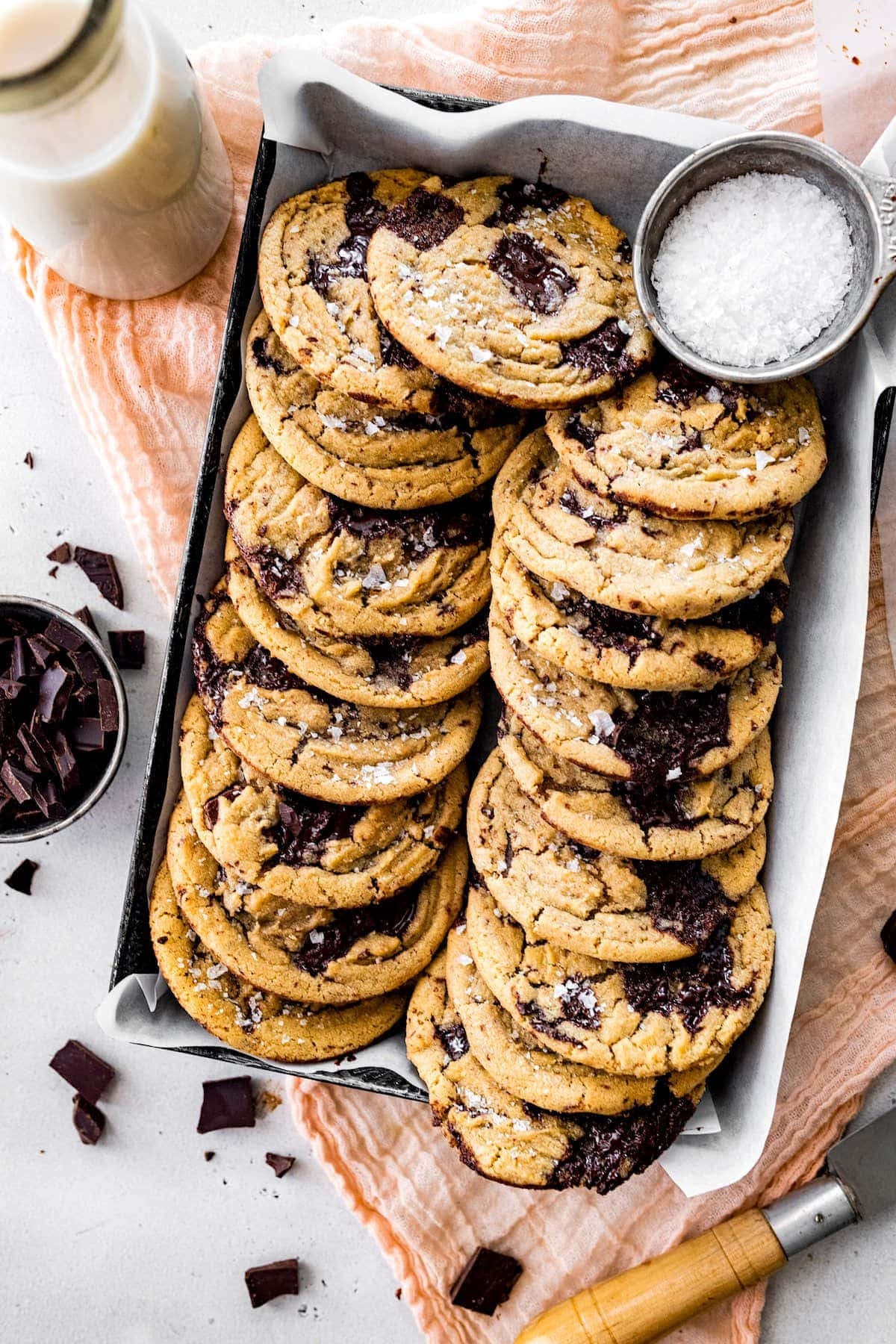 Cookie 桌布 壁紙 — 堆疊的巧克力曲奇配以片狀鹽和牛奶瓶，置於柔軟的桃色布料上。