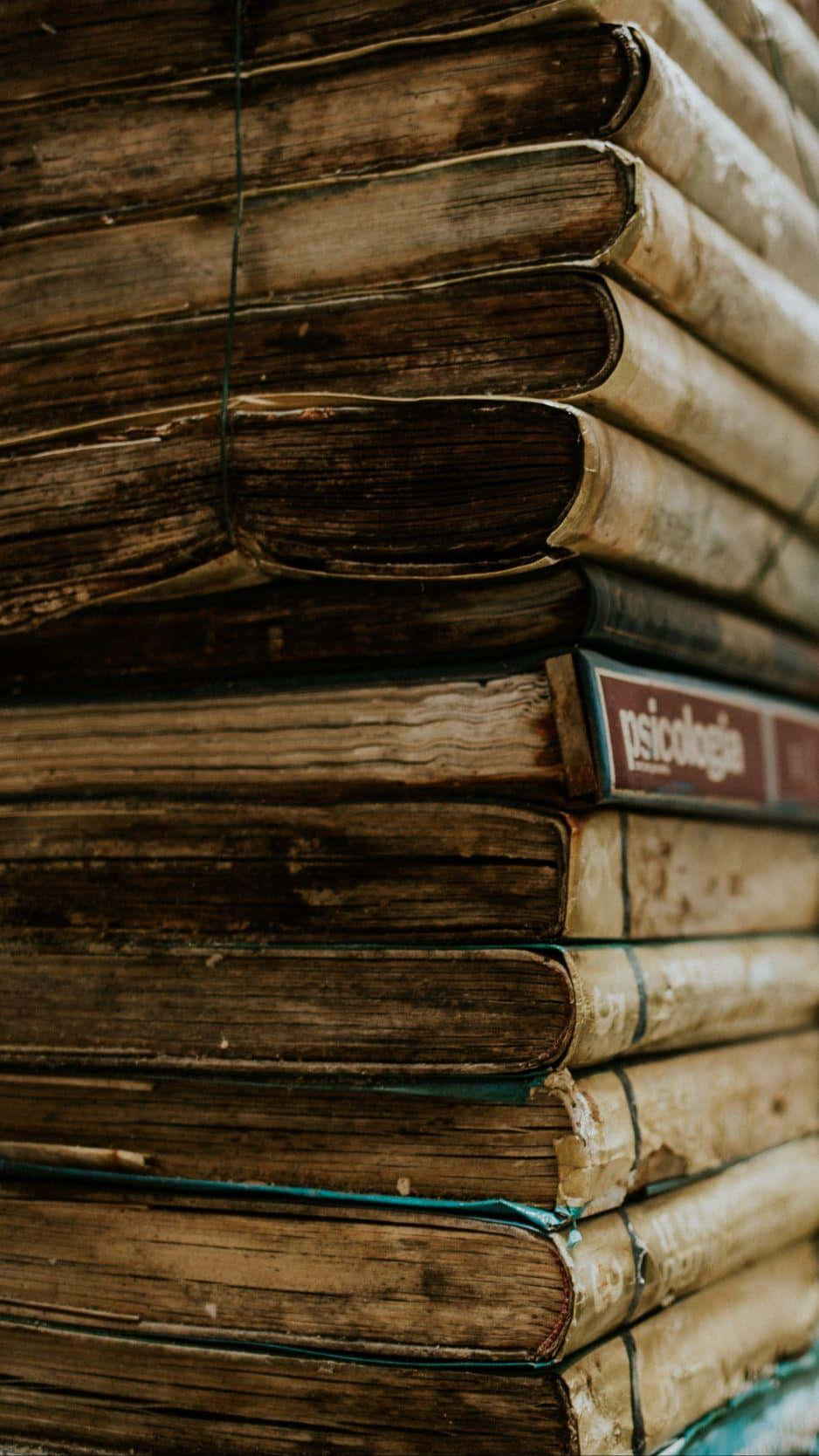 books 桌布 壁紙 — 堆疊的復古書籍特寫，磨損的書脊和褪色的裝訂揭示了它們的年代和使用痕跡。
