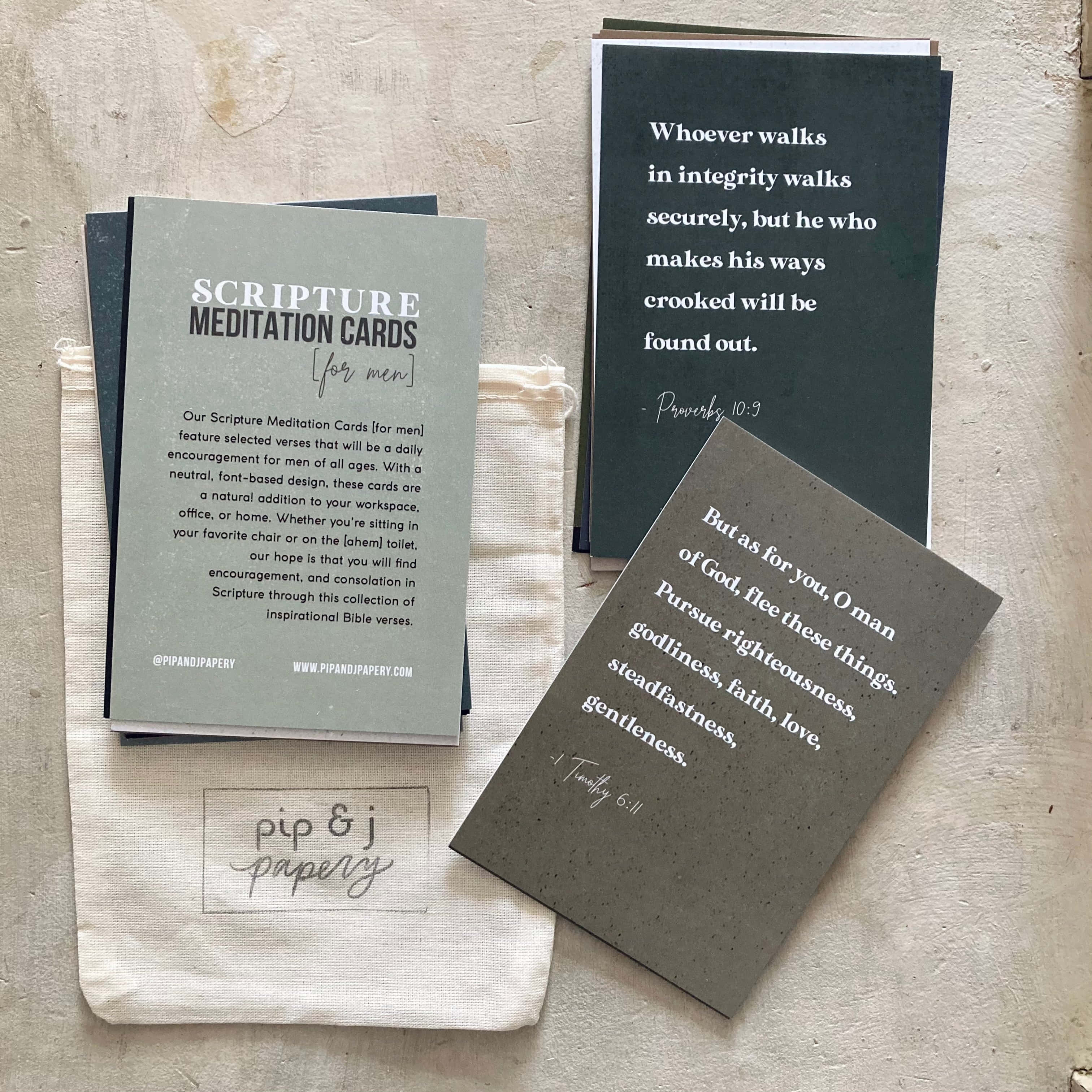Scripture 桌布 壁紙 — 堆疊的經文默想卡，上面有聖經經文，放在一個帶有 pip & j papery 品牌標誌的質感米色布袋上。