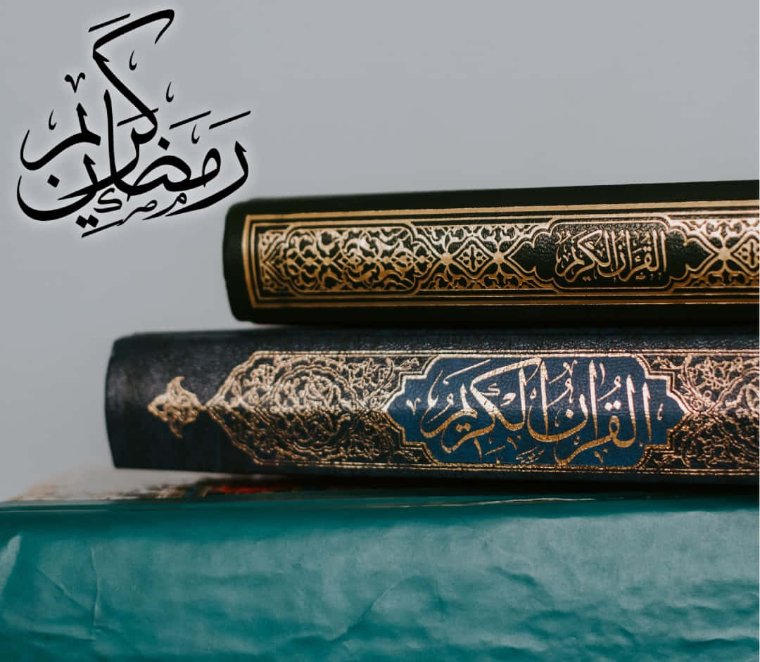 Ramadan 桌布 壁紙 — 堆疊的華麗伊斯蘭書籍，帶有金色書法，放置在青綠色紙上，背景為柔和的灰色。