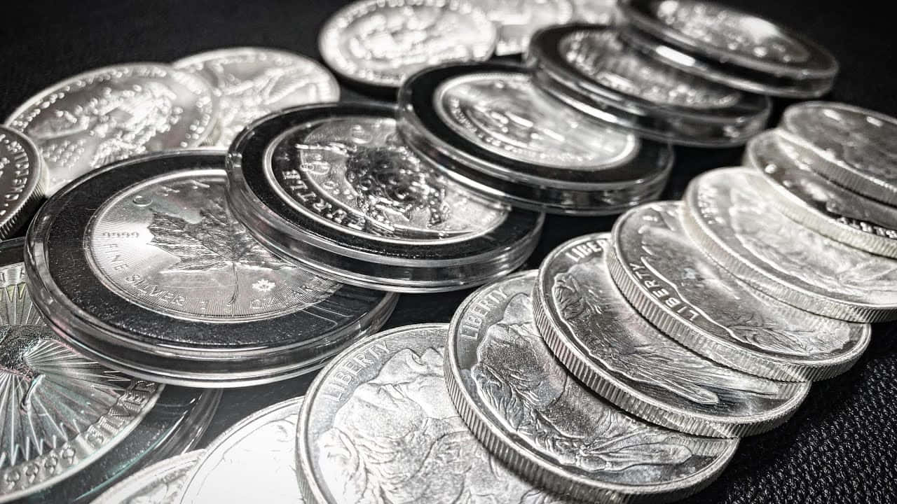 黑白 桌布 壁紙 — 堆疊的銀幣帶有精細雕刻，在聚焦光線下於深色紋理背景上閃閃發光。