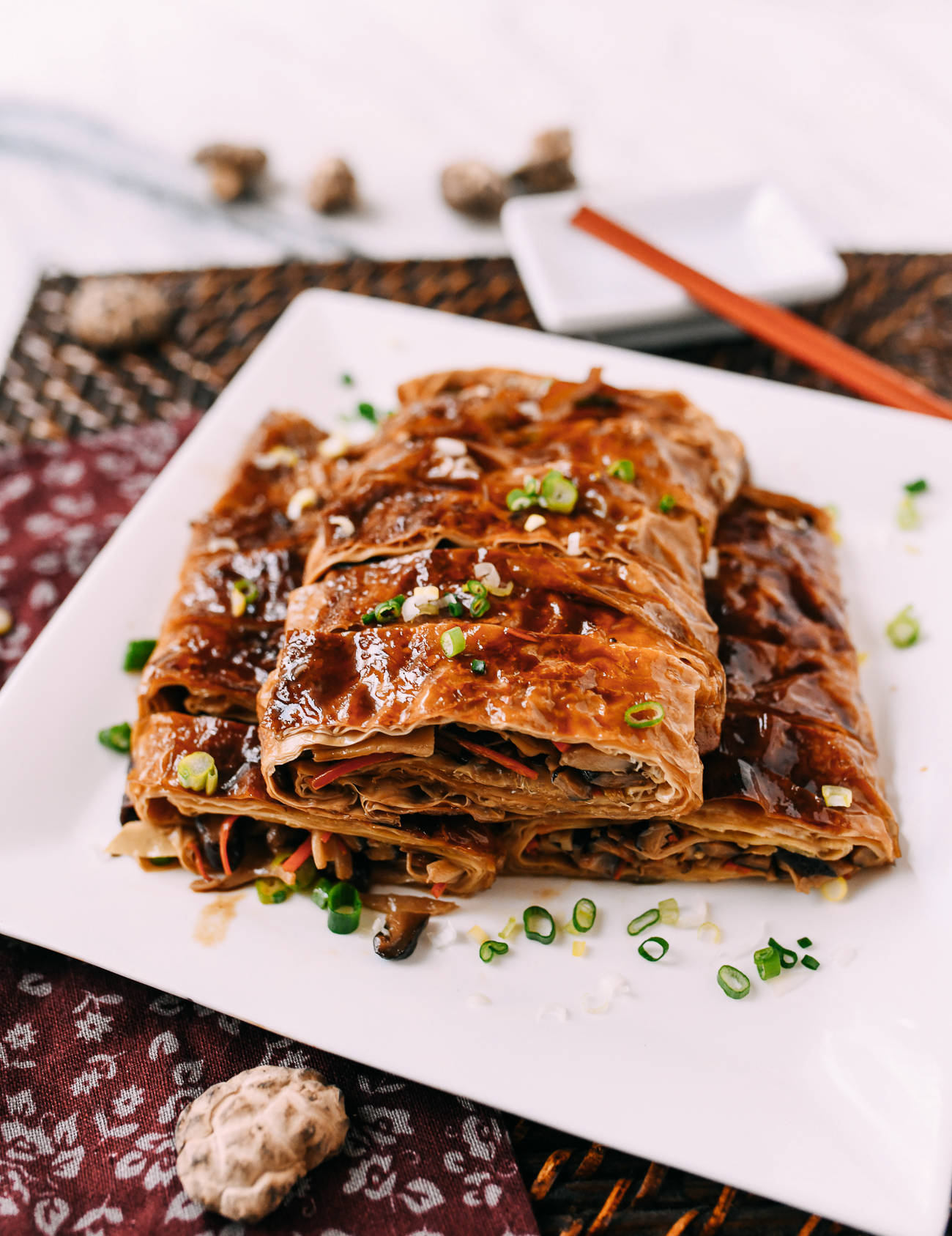 healthy 桌布 壁紙 — 堆疊的鹹味蔬菜卷，淋上深色醬汁，並以切碎的青蔥裝飾，放在白色盤子上。