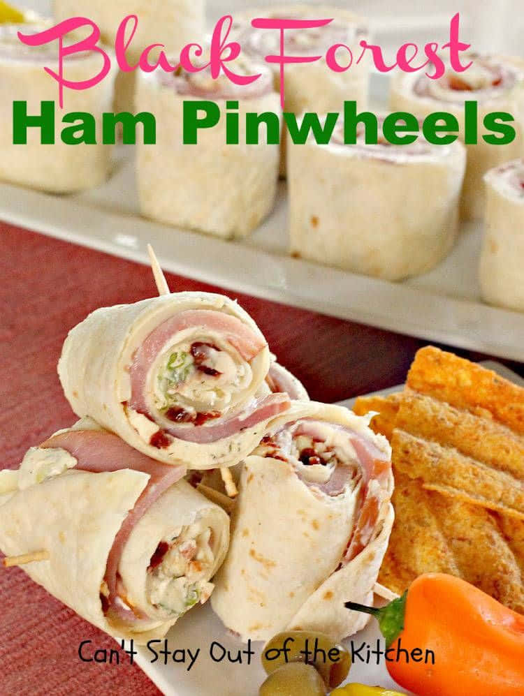 Black Forest Ham 桌布 壁紙 — 堆疊的黑森林火腿卷，內有奶油餡料和培根粒，旁邊放有墨西哥玉米片和一個辣椒，置於紅布上。