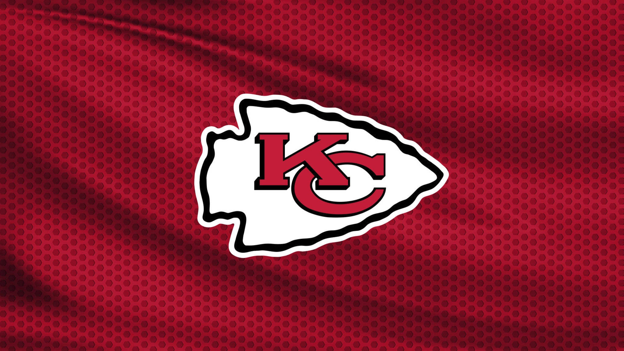 Kansas City Chiefs Logo 桌布 壁紙 — 堪薩斯城酋長隊標誌以紅白配色顯示在帶紋理的紅色布料背景上。