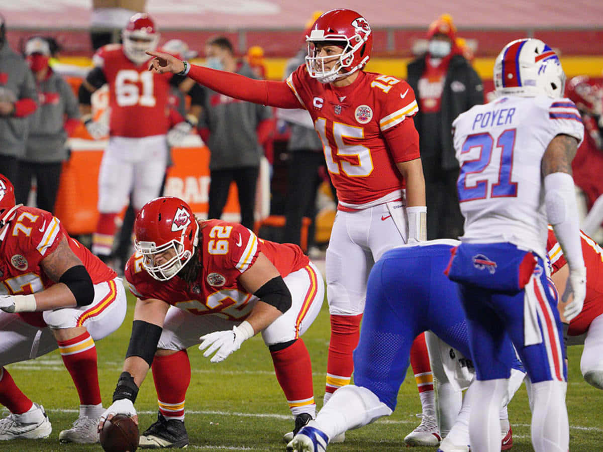 NFL 桌布 壁紙 — 堪薩斯城酋長隊的四分衛身穿紅色球衣，在夜間美式足球比賽中指向場地，球員們在場上列隊。