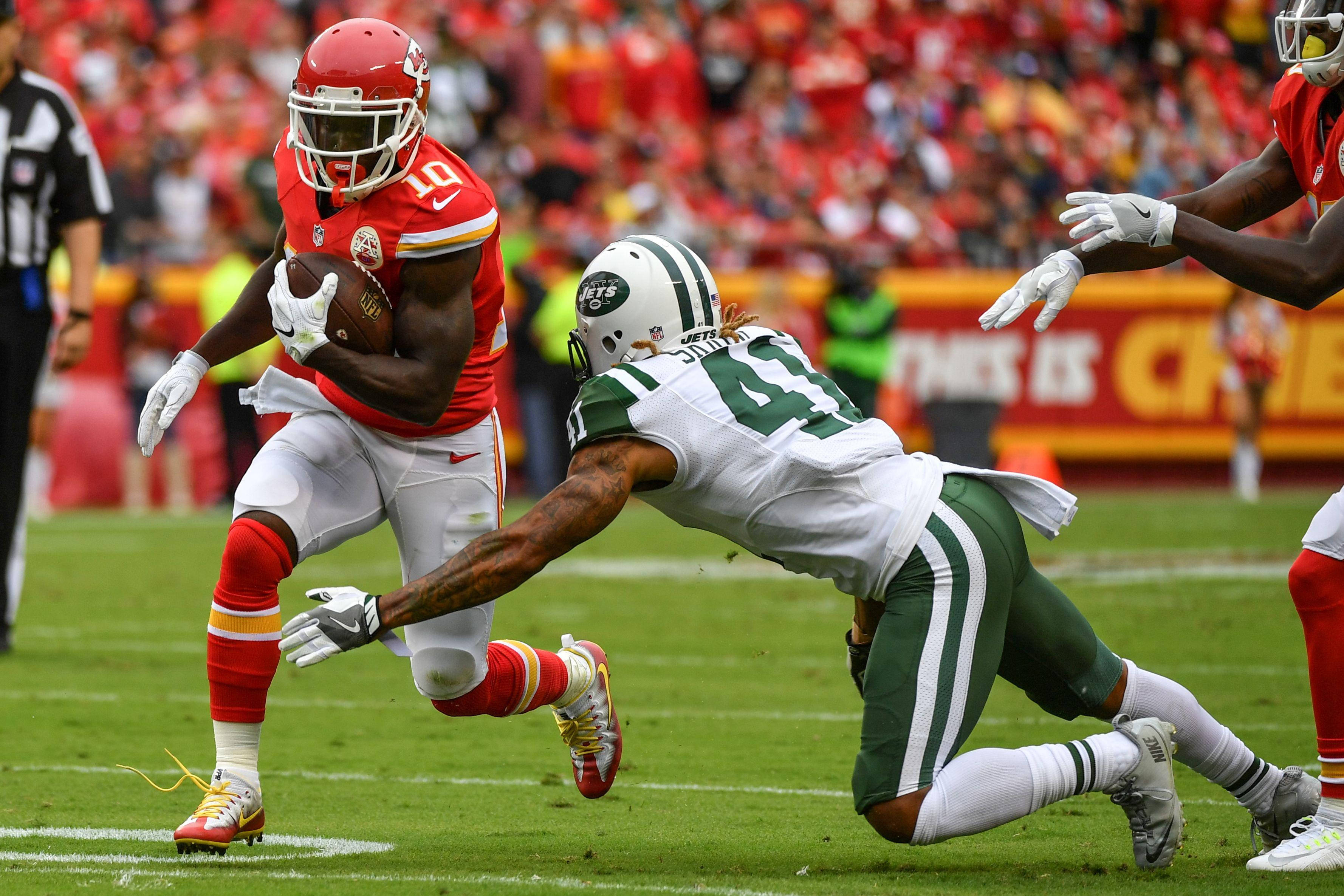 Tyreek Hill 桌布 壁紙 — 堪薩斯城酋長隊的跑衛身穿紅色球衣，在陽光明媚的足球場上突破紐約噴射機隊防守球員的擒抱。