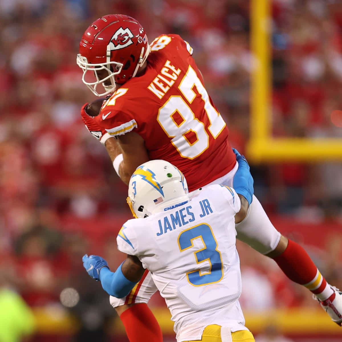 NFL 桌布 壁紙 — 堪薩斯城酋長隊的近端鋒在激烈的夜間美式足球比賽中跳過洛杉磯電光隊的防守球員。