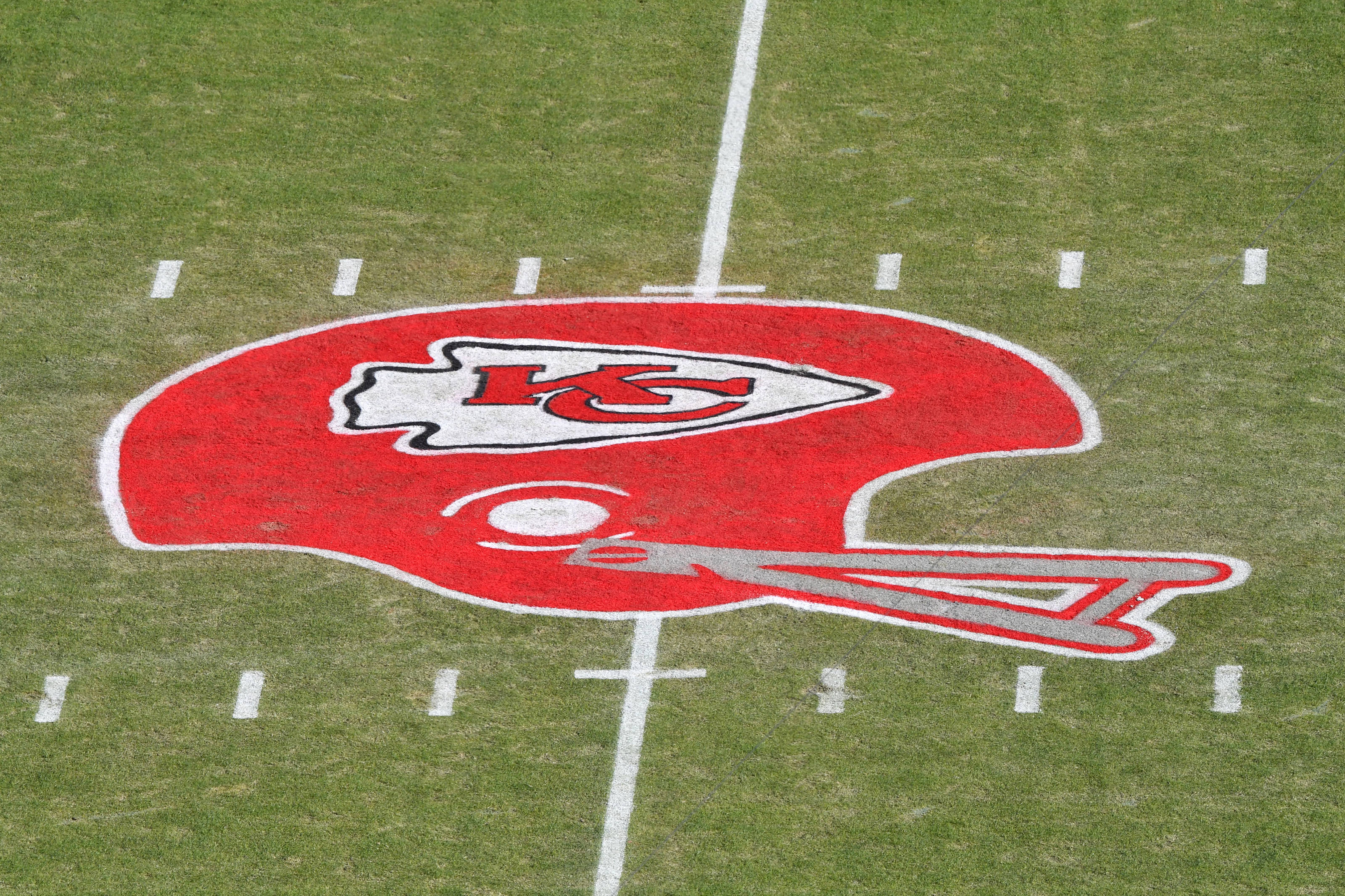 Kansas City Chiefs Logo 桌布 壁紙 — 堪薩斯城酋長隊頭盔標誌的特寫，以紅、白、銀色繪製在帶有碼線的綠色足球場上。