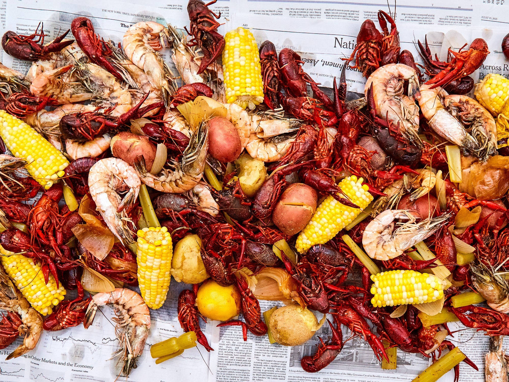 Seafood 桌布 壁紙 — 報紙上色彩繽紛的水煮小龍蝦、蝦、玉米和馬鈴薯，展示經典的卡真水煮盛宴。
