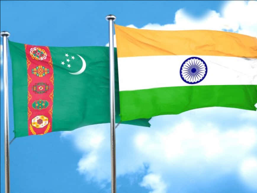 India Flag 桌布 壁紙 — 塔吉克和印度國旗在明亮的藍天和蓬鬆的白雲下並排飄揚。