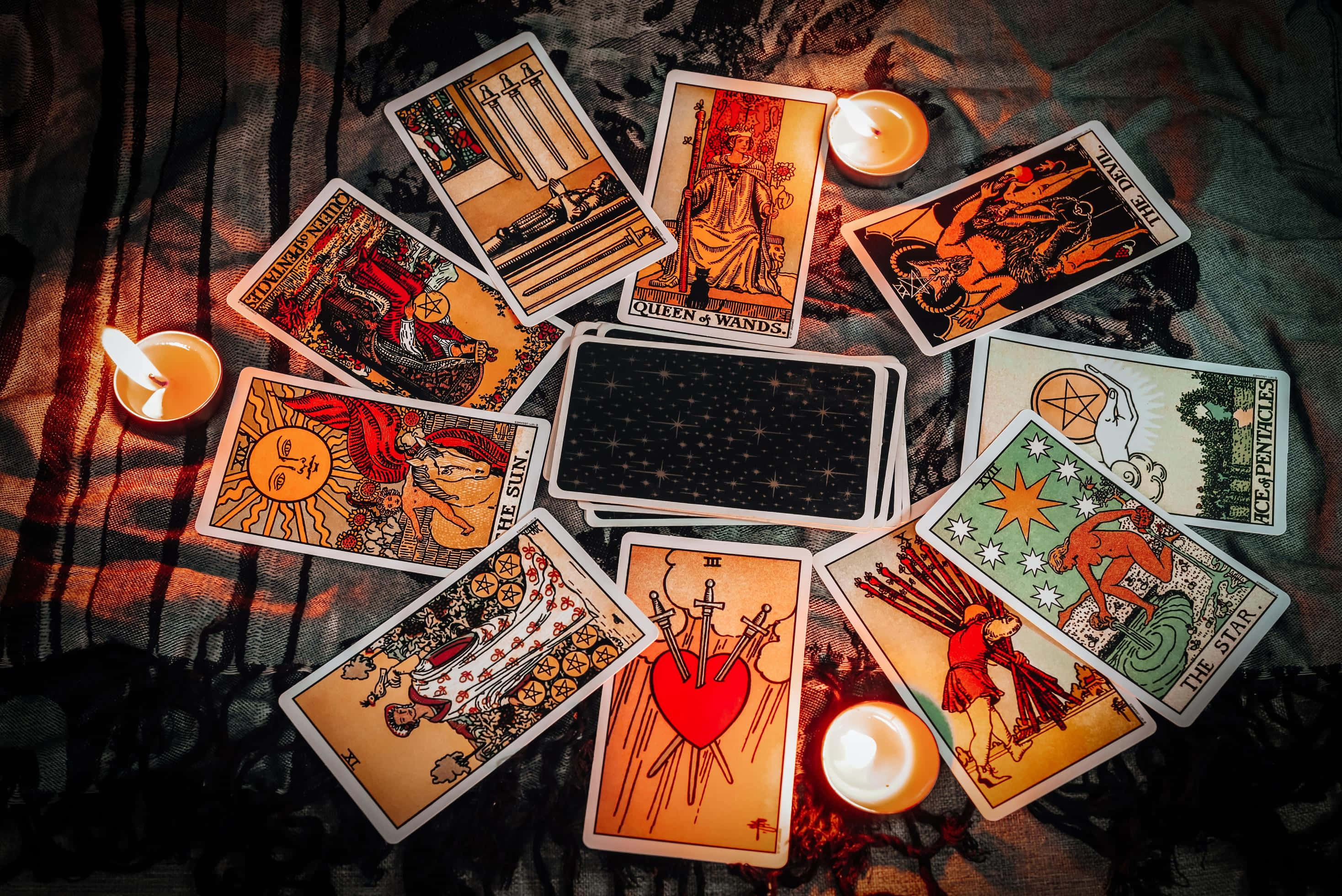 Tarot Card 桌布 壁紙 — 塔羅牌散落在深色布料上，溫暖的燭光在周圍投下柔和陰影。