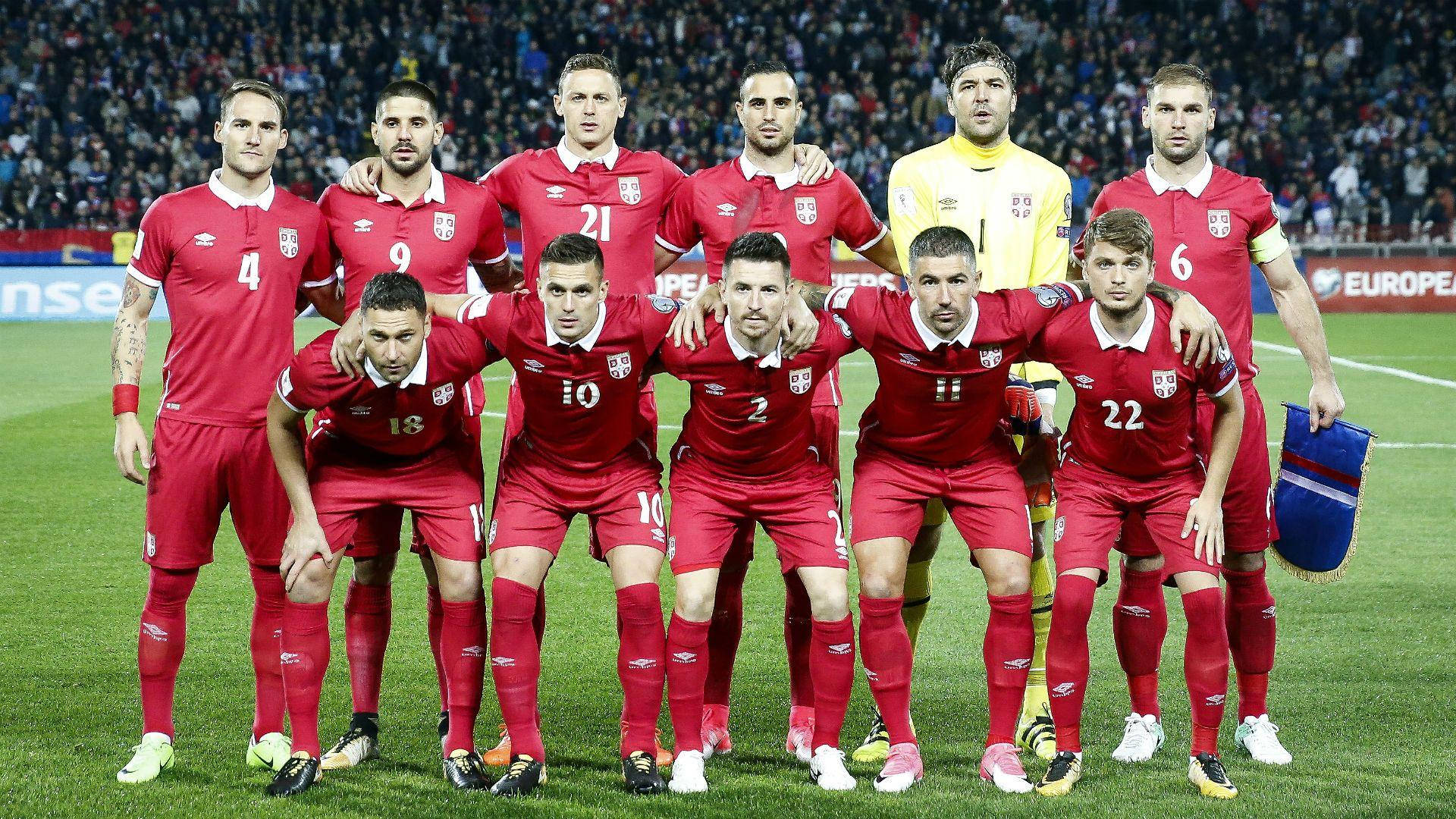 Serbia 桌布 壁紙 — 塞爾維亞國家足球隊身穿紅色球衣，在明亮的燈光下於綠色球場上拍攝團體照。