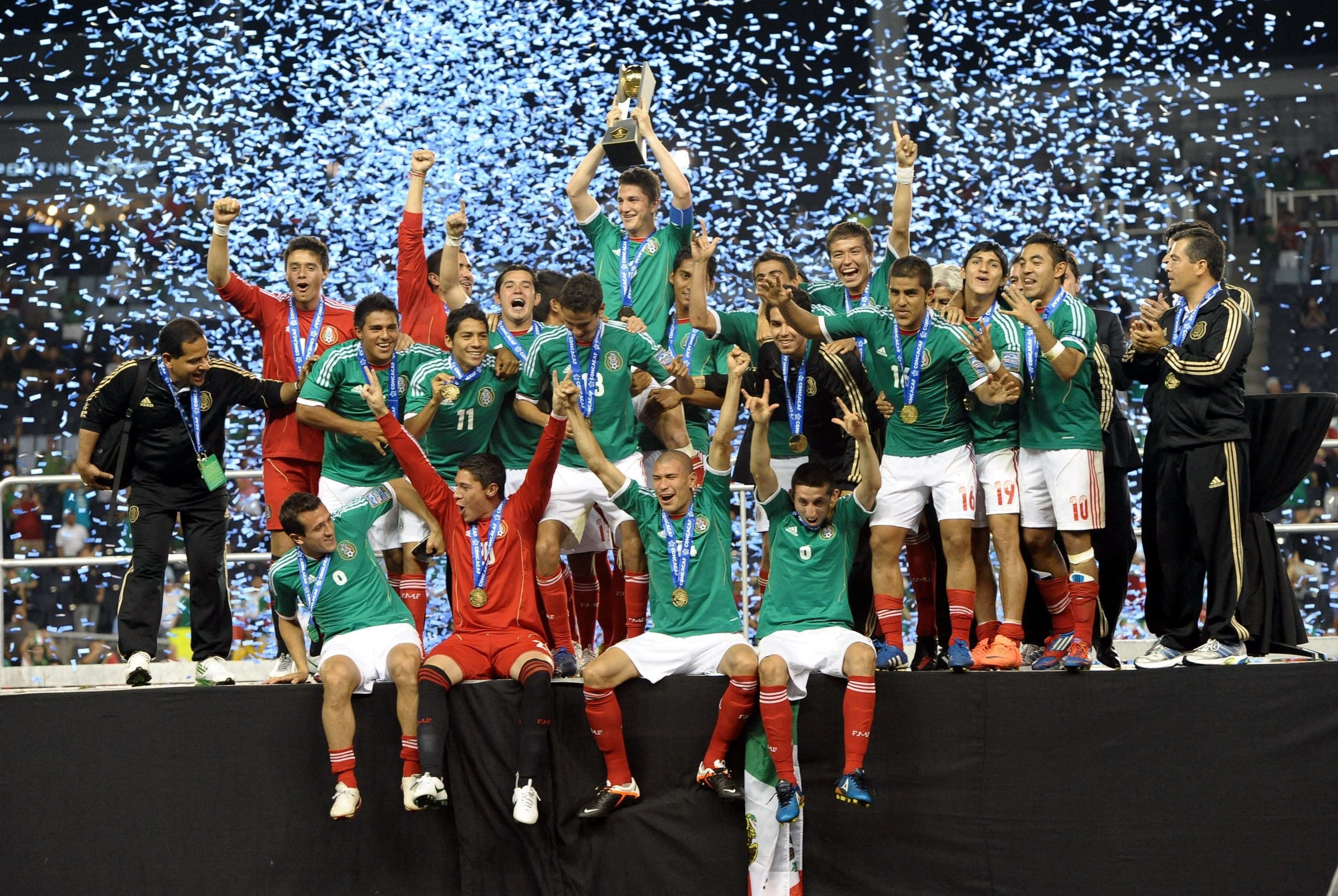 Mexico Soccer 桌布 壁紙 — 墨西哥足球隊在頒獎台上慶祝勝利，獎盃和五彩紙屑在他們周圍飄落。