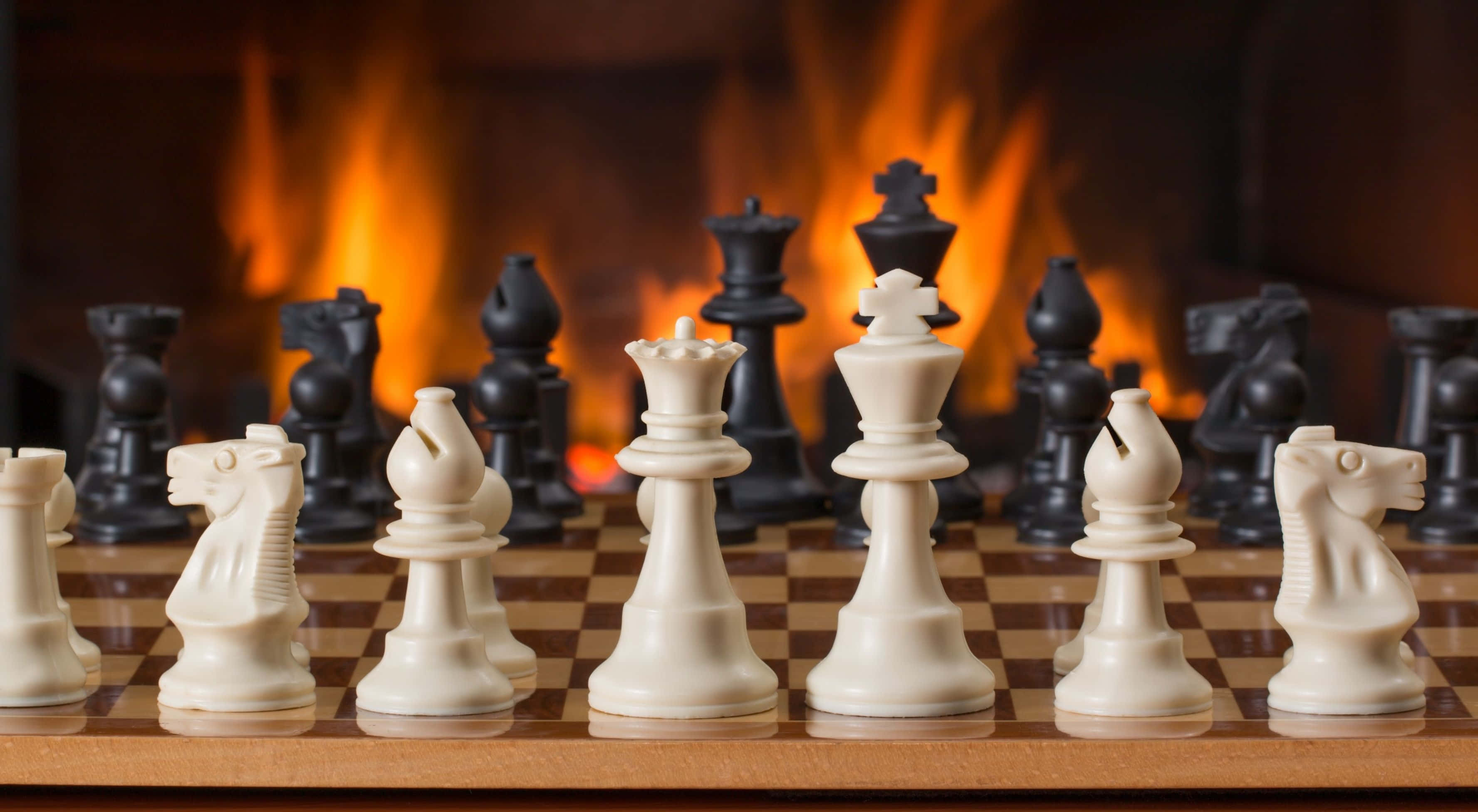壁爐前木製棋盤上的西洋棋棋子 壁紙