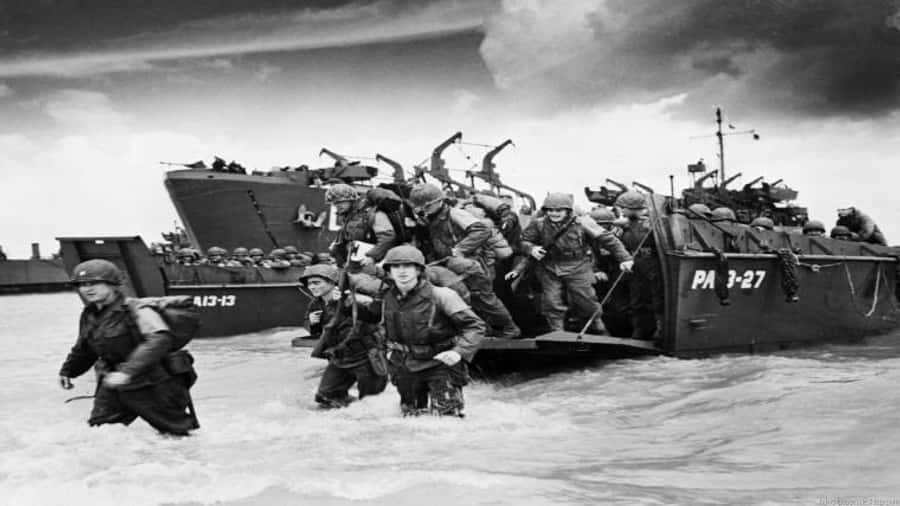 soldier 桌布 壁紙 — 士兵戴著頭盔在暴風雨的天空下從登陸艇涉水上岸，進行歷史性的兩棲攻擊。