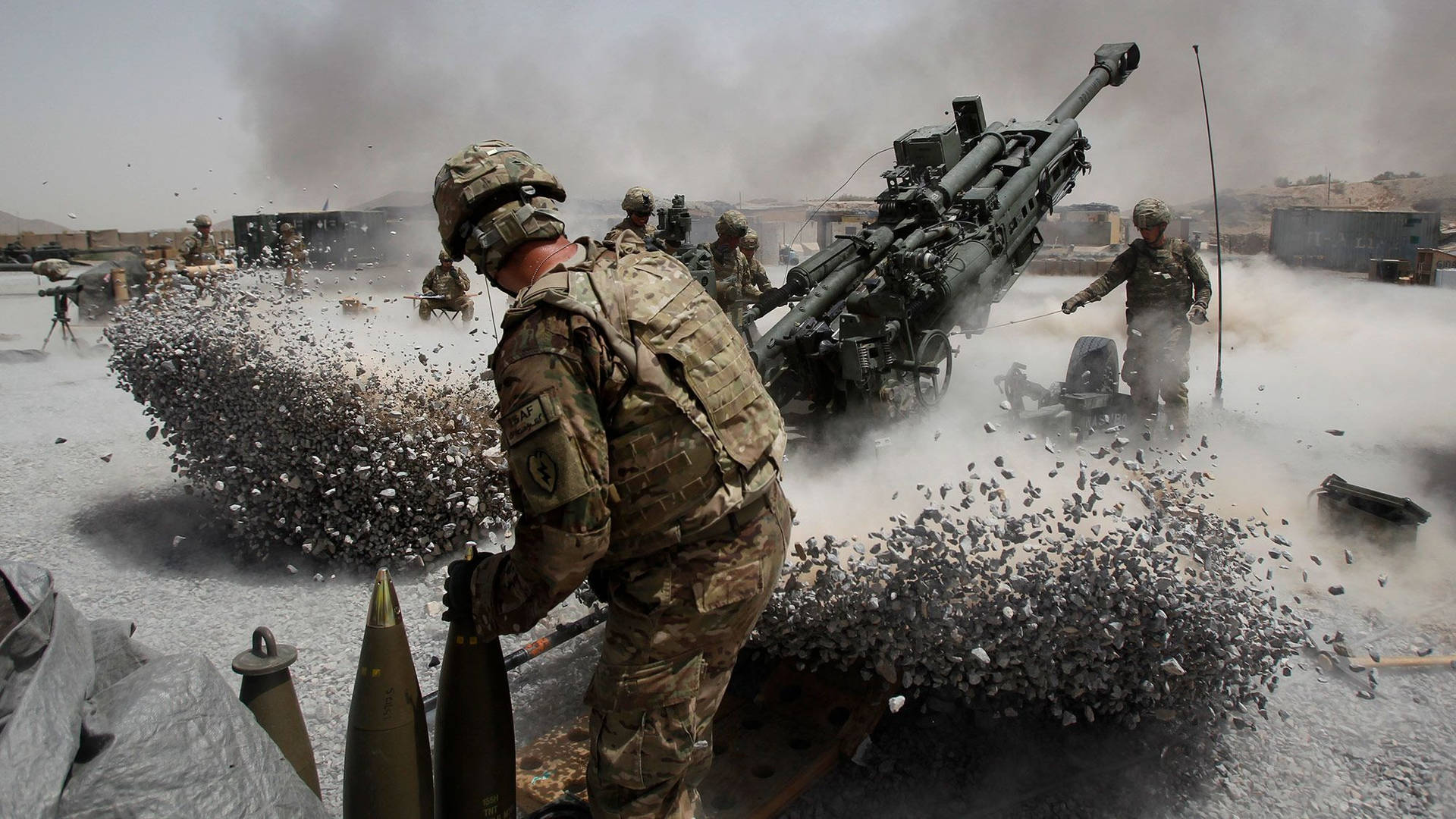 士兵在塵土飛揚的戰鬥區域發射火炮。 — 軍隊 壁紙